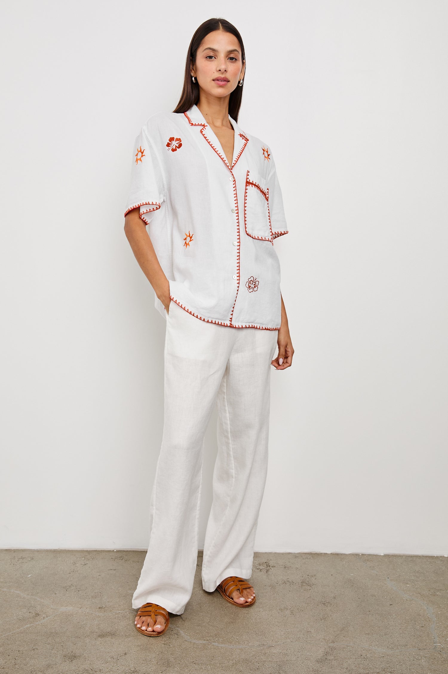 Island Short-Sleeve, Button-Down Shirt with Flat Collar, Large Chest Patch Pocket, Embroidered Decorative Trim and Embroidered Flowers and Sun in Red and Yellows in White Colorway - Front View Featured on Model 