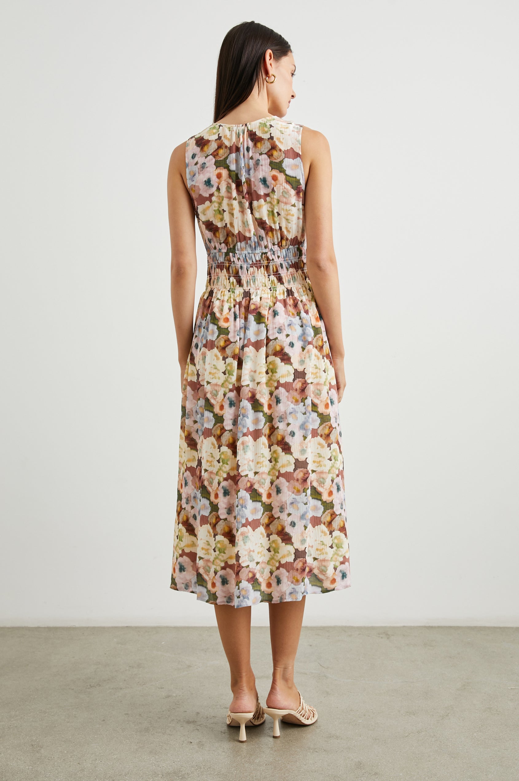 Izzy Sleeveless Midi Dress with Wide Smocked Shoulder Straps, a Smocked Waist and a Deep V Neck, in Painted Floral Colorway, in Browns, Yellows, Pinks, Blues and Greens - Back Full Body View Featured on Model 
