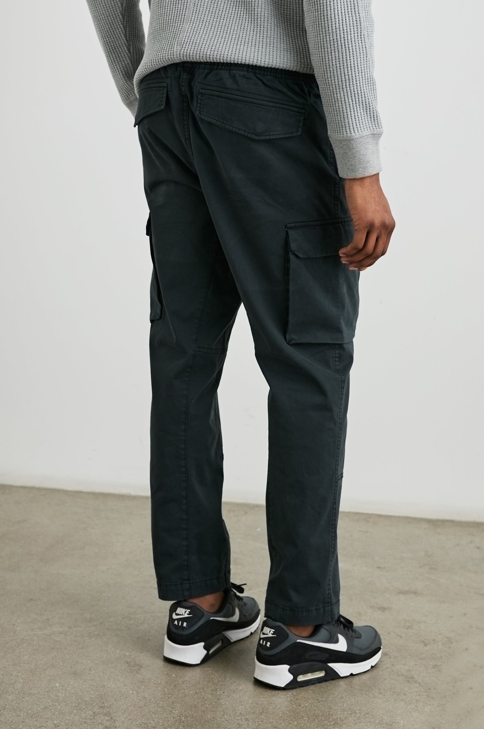 Jaiden Pants with an Elastic, Button Waist with Zip Fly, Two Front Pockets, Two Side Flap Pockets, and Two Back Flap Pockets in Black Colorway - Back View Featured on Model