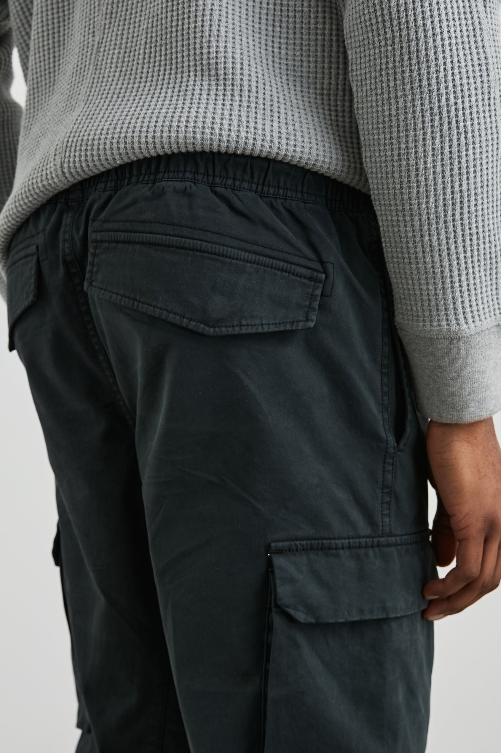 Jaiden Pants with an Elastic, Button Waist with Zip Fly, Two Front Pockets, Two Side Flap Pockets, and Two Back Flap Pockets in Black Colorway - Back View Featured on Model