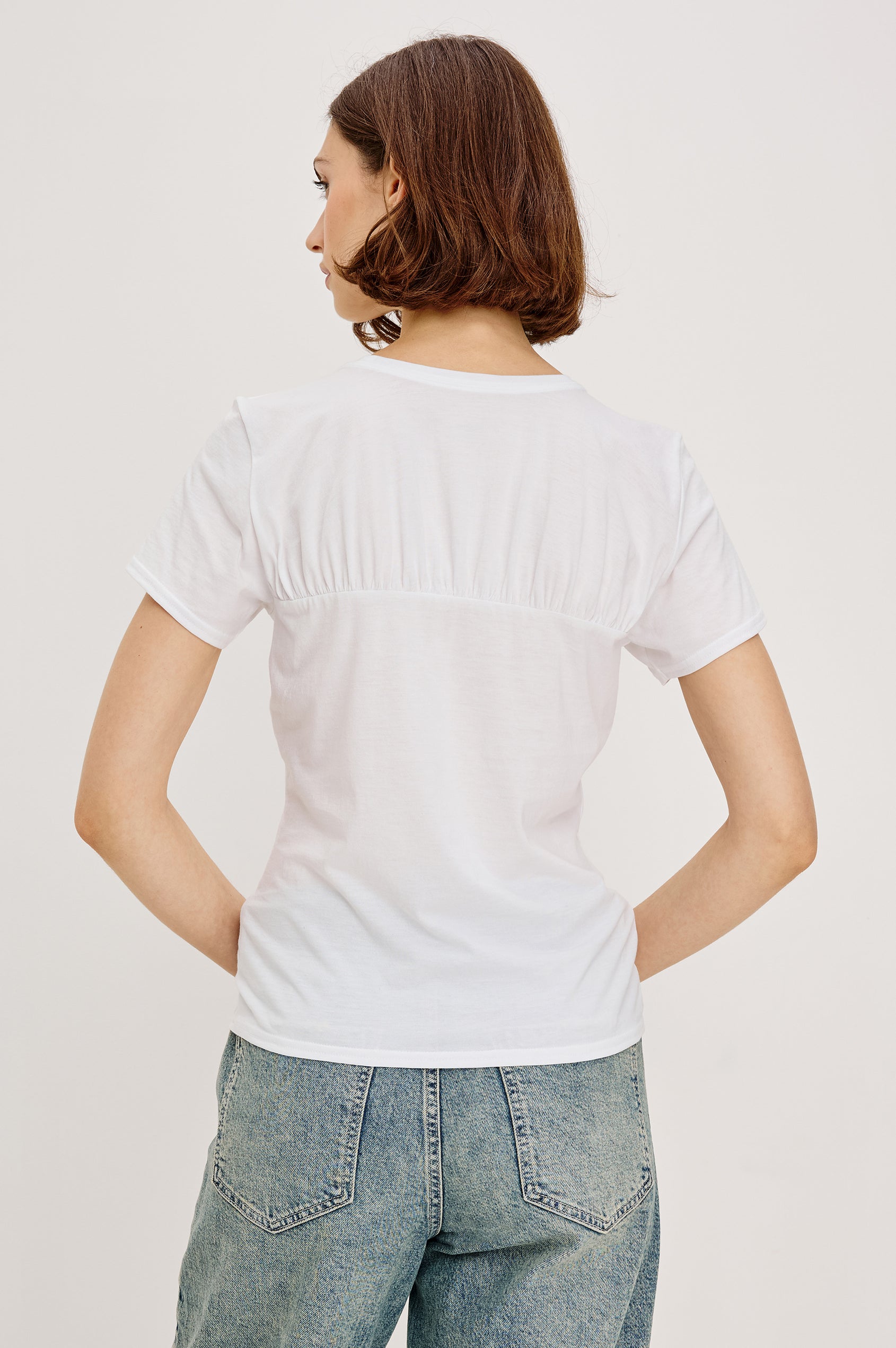 Janis short-sleeve cotton t-shirt with a sweetheart neckline and gathered, shirred detailing at the chest in White Colorway - back view featured on model with shirt tucked in and styled with a western belt.