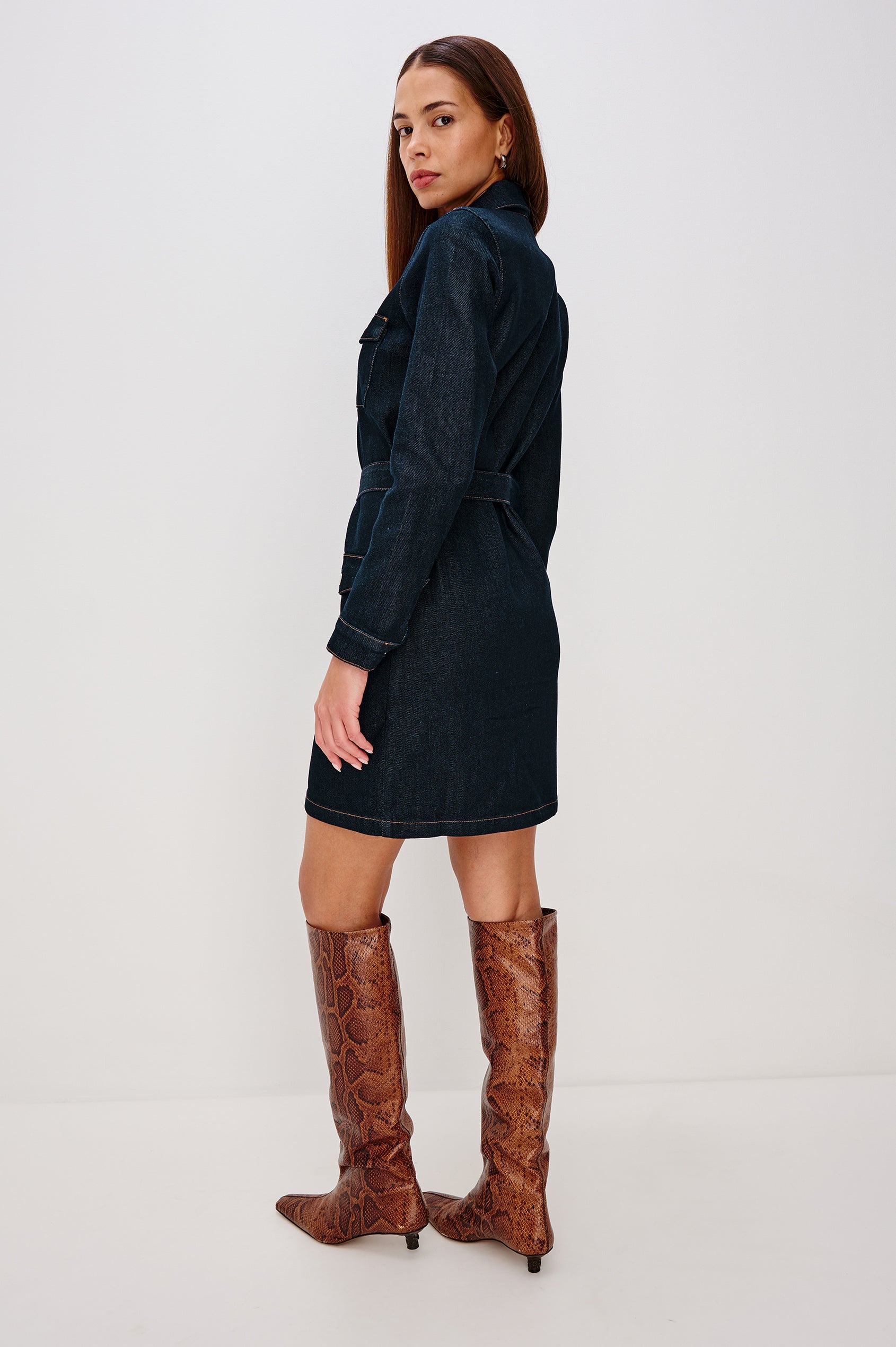 Jefferson is a long sleeve mini denim dress, featuring utility-inspired details and an o-ring adjustable waist belt in Midnight Blue colorway, a rinse wash. Back full body view featured on model.