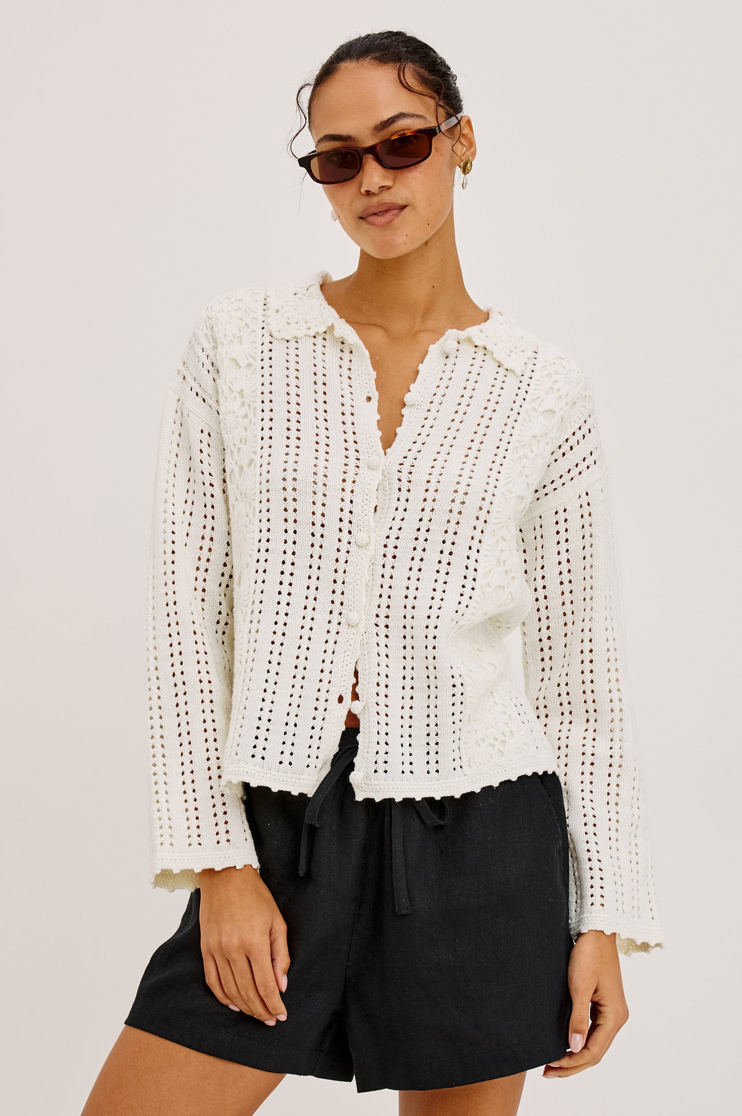 Jenni Cardigan Sweater in Open Weave Cotton Blend Pointelle Knit With Long Sleeves, Crochet Button-Loop Closures, Floral Detailing, and Scalloped Trim in Ivory Colorway - Upper Body Front View Featured on Model
