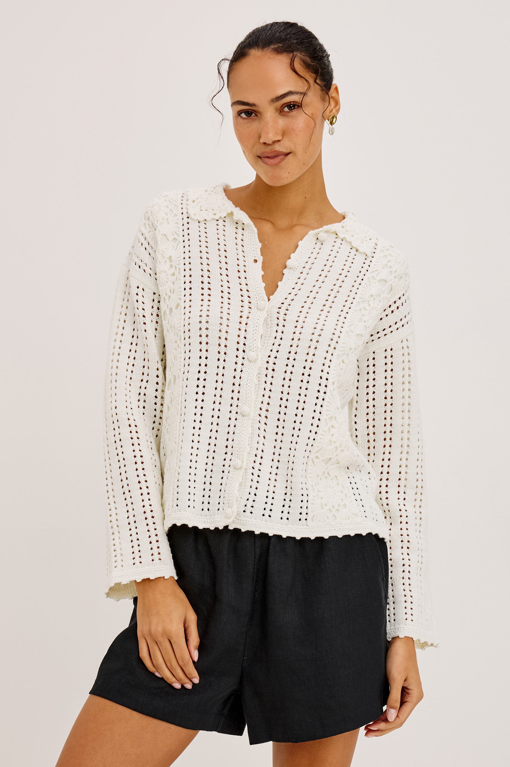 Jenni Cardigan Sweater in Open Weave Cotton Blend Pointelle Knit With Long Sleeves, Crochet Button-Loop Closures, Floral Detailing, and Scalloped Trim in Ivory Colorway - Upper Body Front View Featured on Model