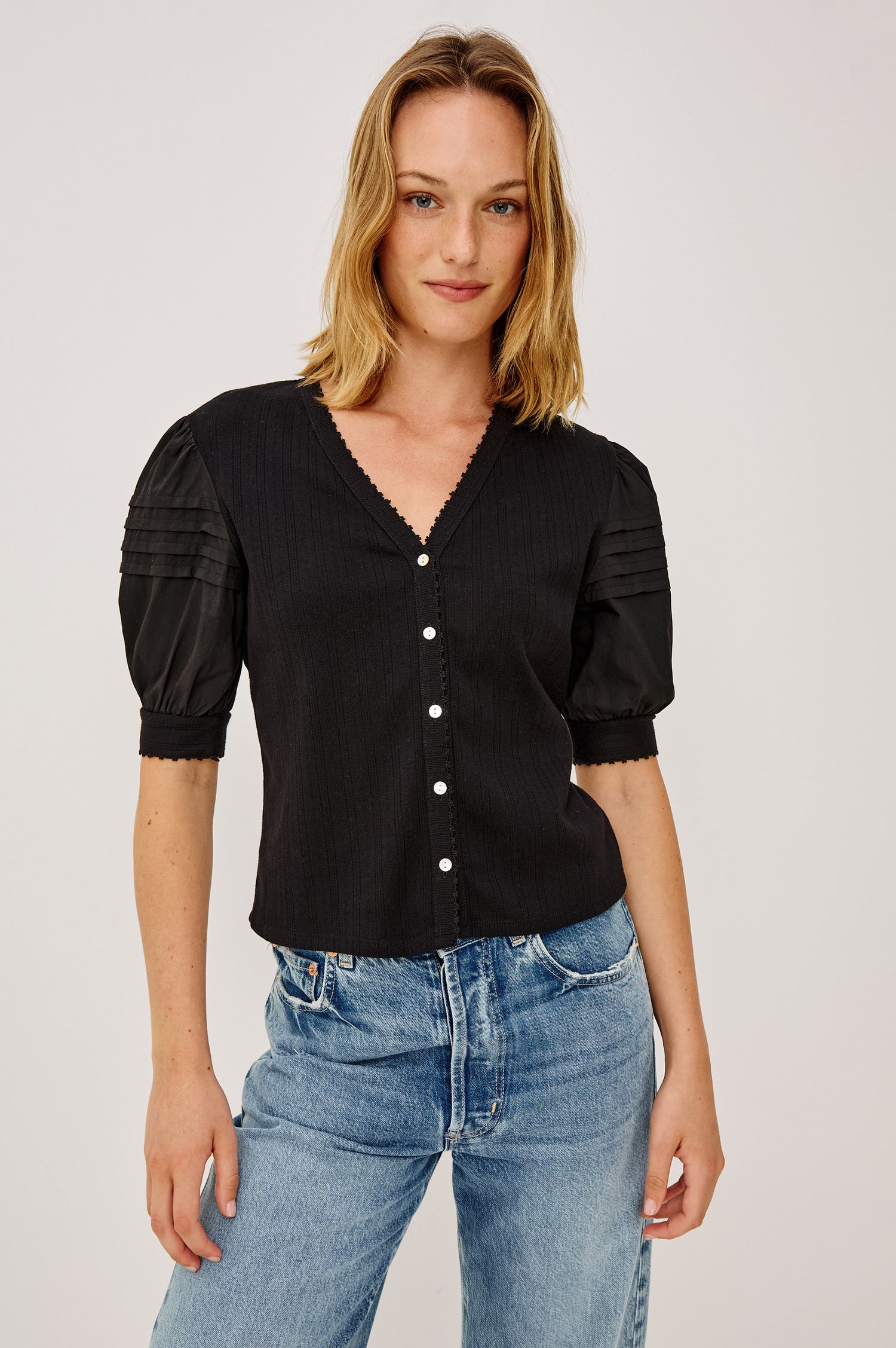 Jessie Top in Pointelle With V-Neckline, Front Buttons, Short Cuffed Puff Sleeves, and Relaxed Fit in Black Colorway - Upper Body Front View Featured on Model