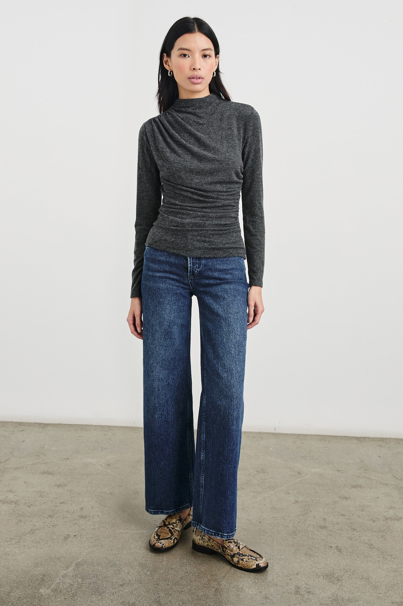 Joelle Long Sleeve Top with An Asymmetrical Mock Neck and Shirring on the Right Shoulder in Charcoal Colorway - Front Full Body View Featured on Model