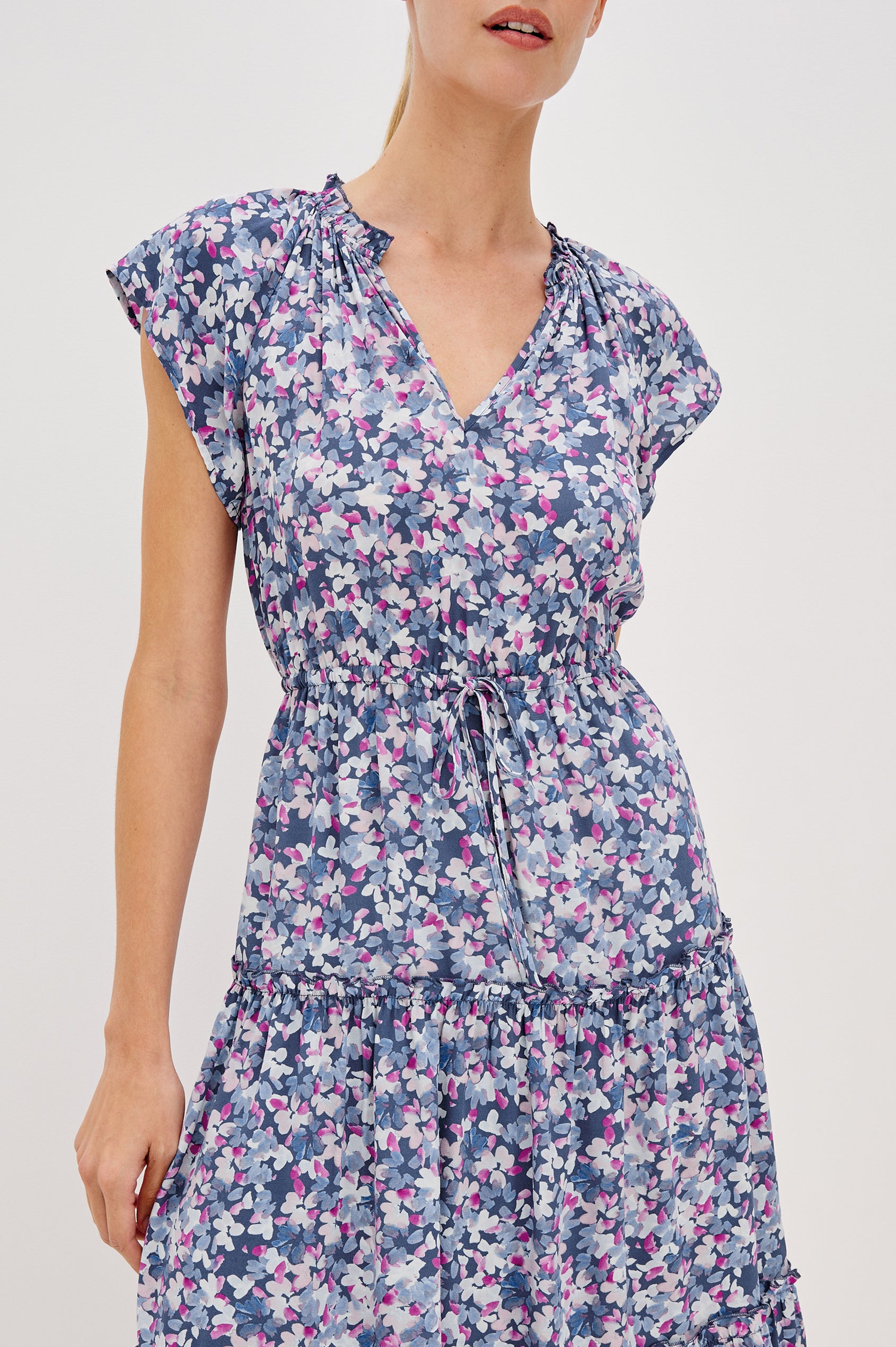 Juni Tiered Midi Dress with a V-Neck, Ruffled Neckline, Short Flutter Sleeves, Drawstring Waist Detail in Blue Blossom Colorway. Front View Shown on Model. 
