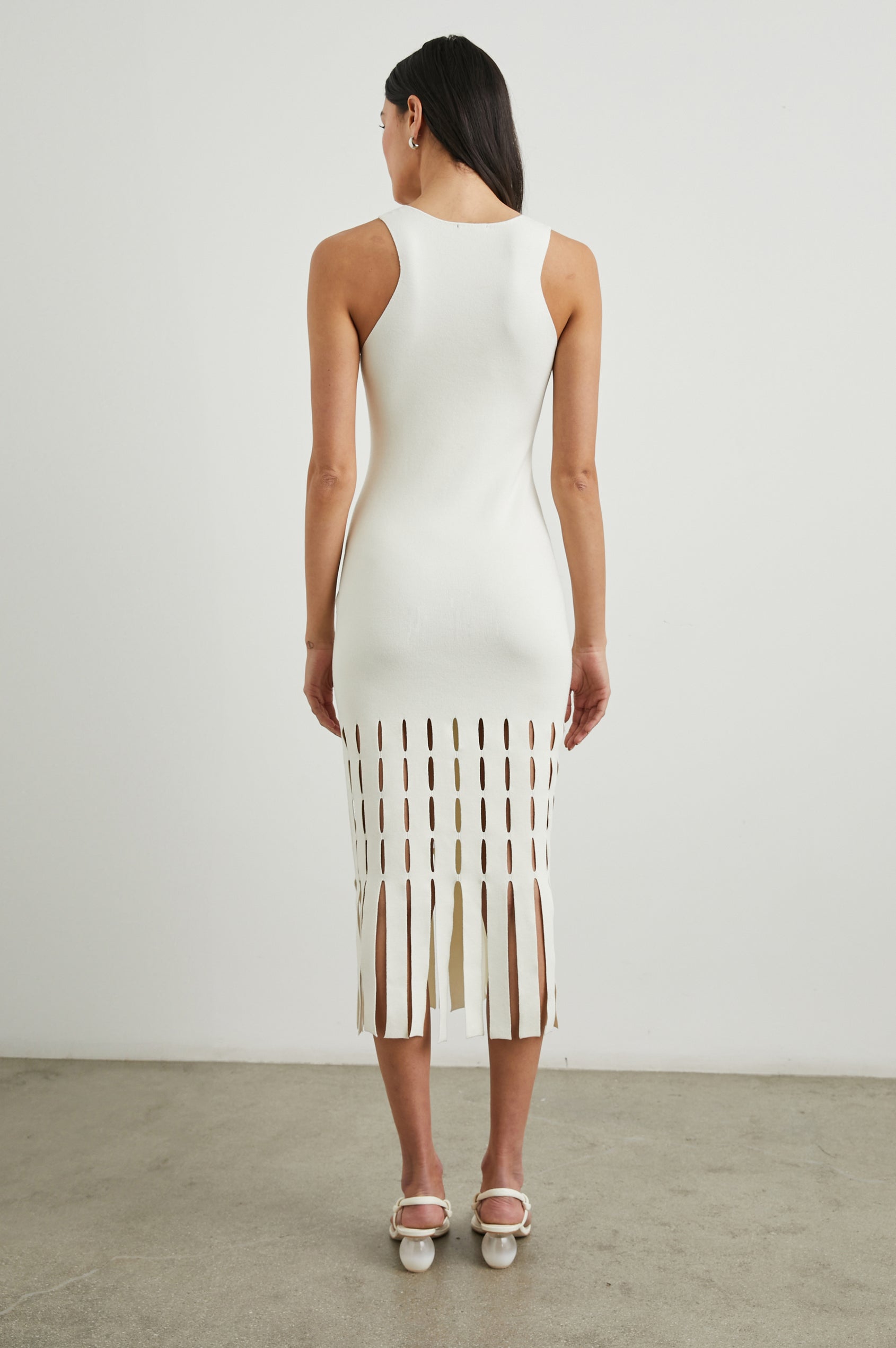 Kaia Sleeveless Midi Dress with a V Neck and Vertical Dashed Cutouts From the Thigh Downward, ending in Panels in White Colorway - Back Full Body View Featured on Model
