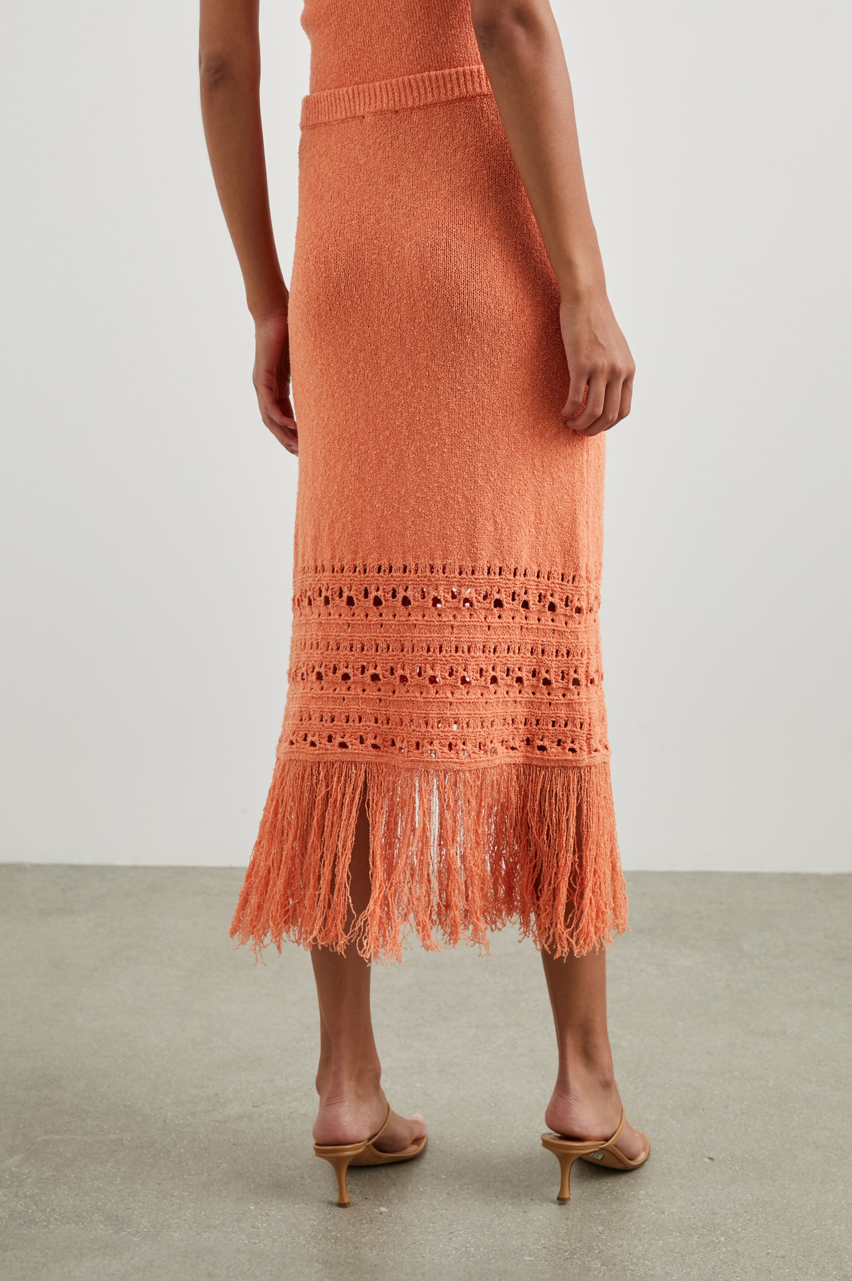 Kaja Midi Skirt with a Crochet Design Along the Bottom and Fringe at the Hem in Persimmon Colorway - Back View Featured on Model  