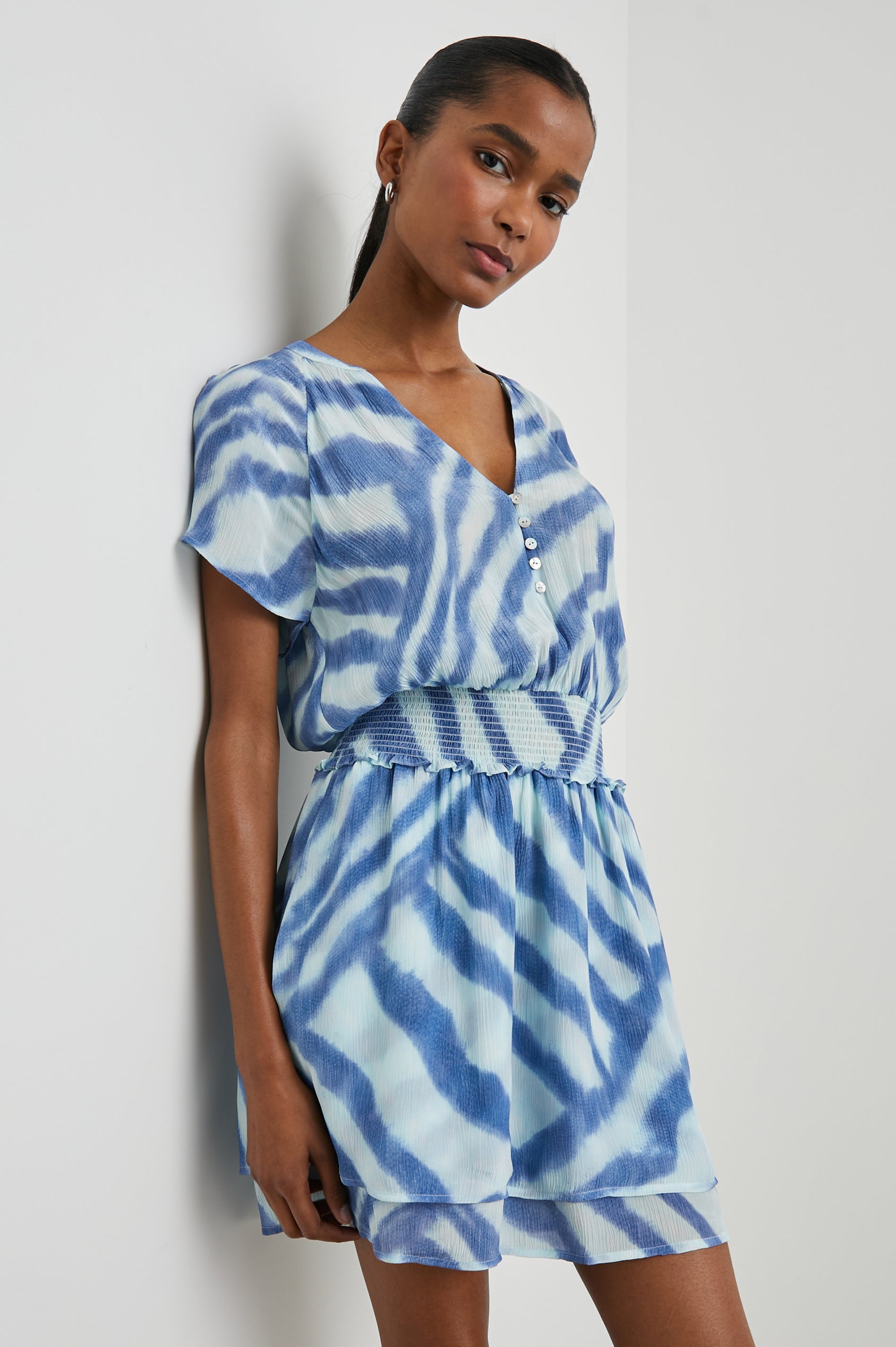 Karla Short Sleeve Mini Dress with a V Neck with Four Buttons, a Shirred Waist and a Double-Layered Skirt in Blue Watercolor Stripes Colorway, Blue on Light Blue - Side View Featured on Model