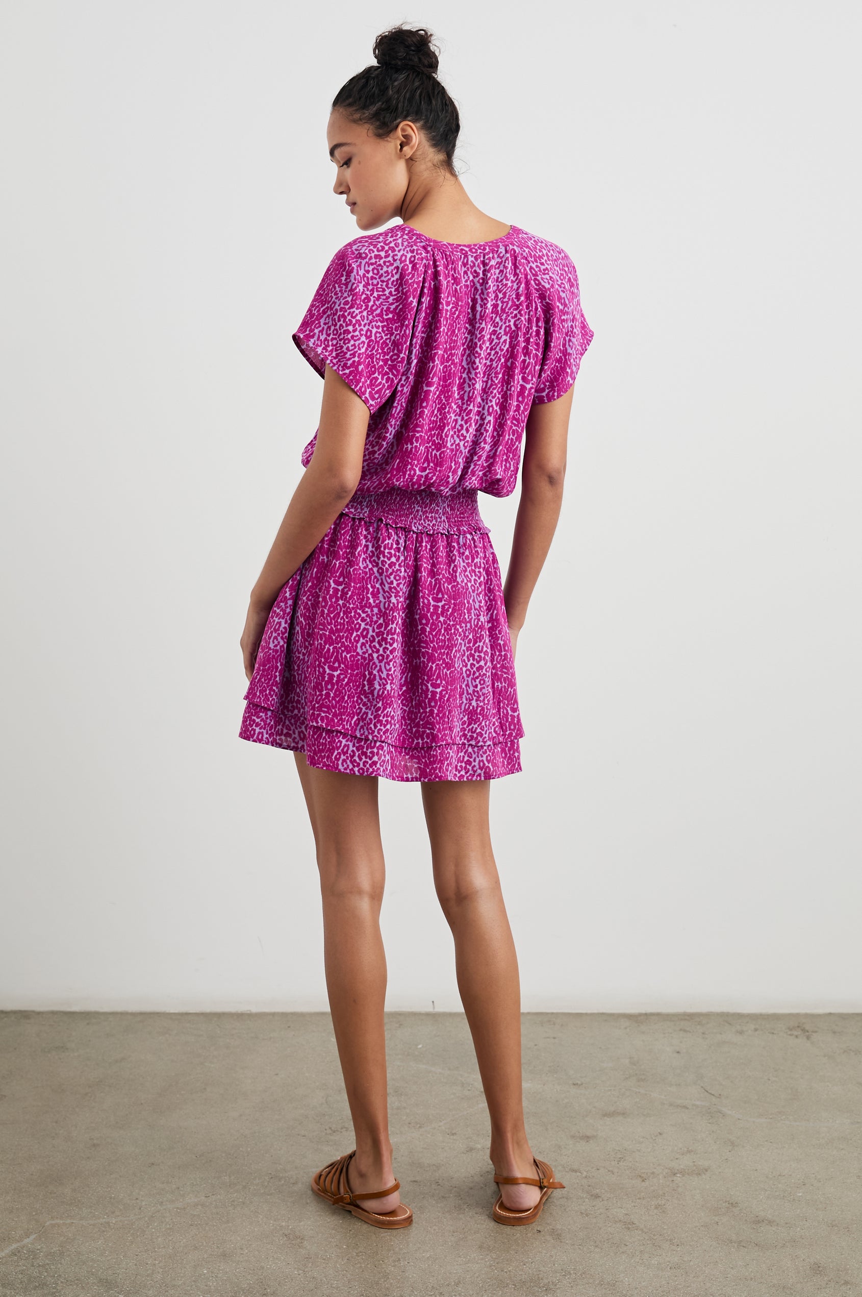 Karla Short Sleeve Mini Dress with a V Neck with Four Buttons, a Shirred Waist and a Double-Layered Skirt in Magenta Cheetah Colorway, Magenta Spots on White - Back Full Body View Featured on Model
