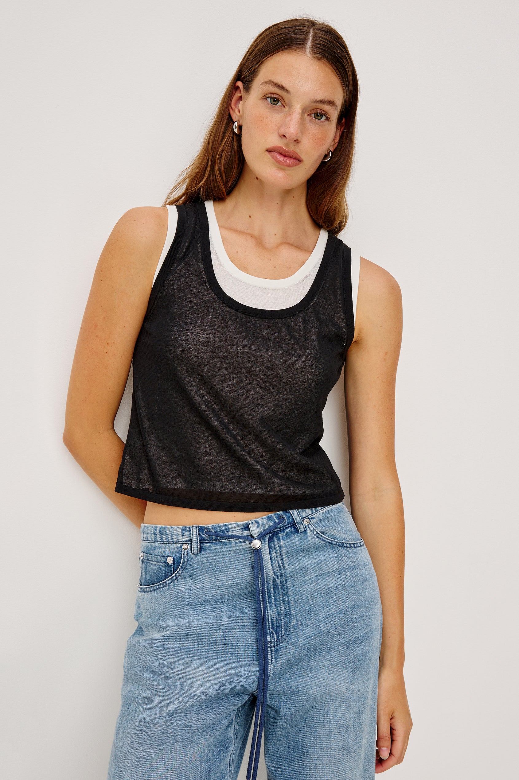 The Kelly is a semi sheer double layered scoop neck tank top, black on top and ivory as under layer. Front view featured on model.