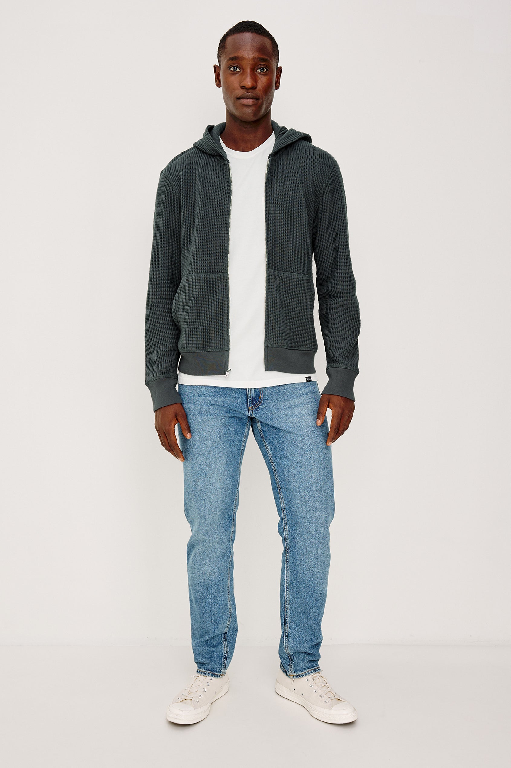 Kenton is a zip front hooded sweatshirt with front patch pockets and ribbed cuffs in Ink colorway. Front full body view featured on model.