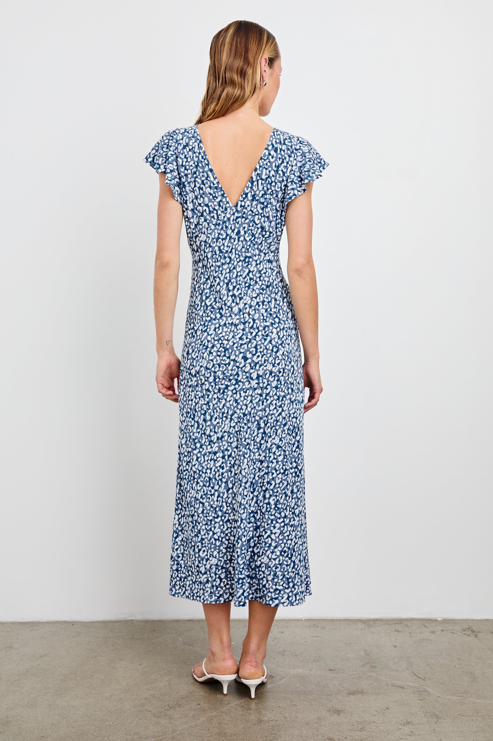 Kenz Midi Dress with Flutter cap Sleeves, and a deep V Neck in Blue Mixed Cheetah Colorway, Spots in Blues and White - Back Full Body View Featured on Model