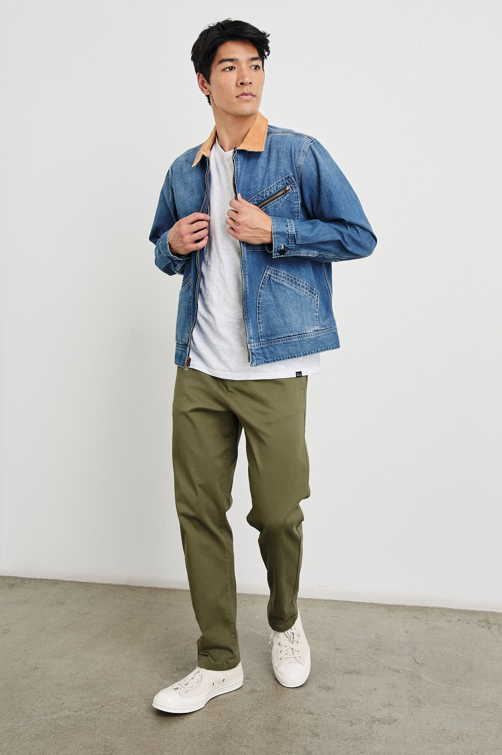 Ketter Zip Up Jacket with Two Curved Front Patch Pockets, a Diagonally Zippered Chest Patch Pocket and Adjustable Button Straps on the Hem in Indigo Patina Wash Colorway, with a Tan Collar - Front Full Body View Featured on Model