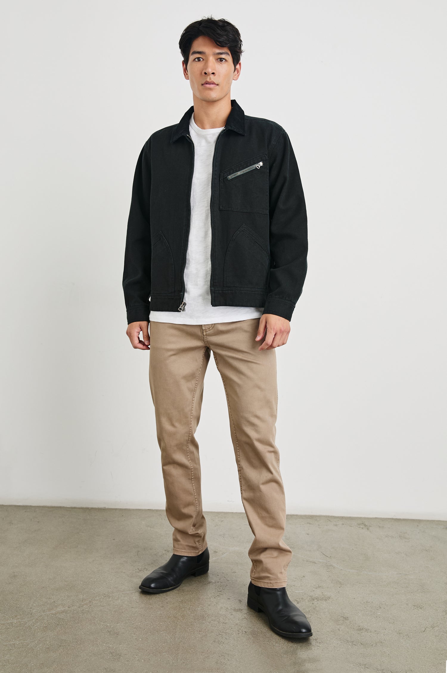 Ketter Zip Up Jacket with Two Curved Front Patch Pockets, a Diagonally Zippered Chest Patch Pocket and Adjustable Button Straps on the Hem in Raven Colorway - Front Full Body View Featured on Model