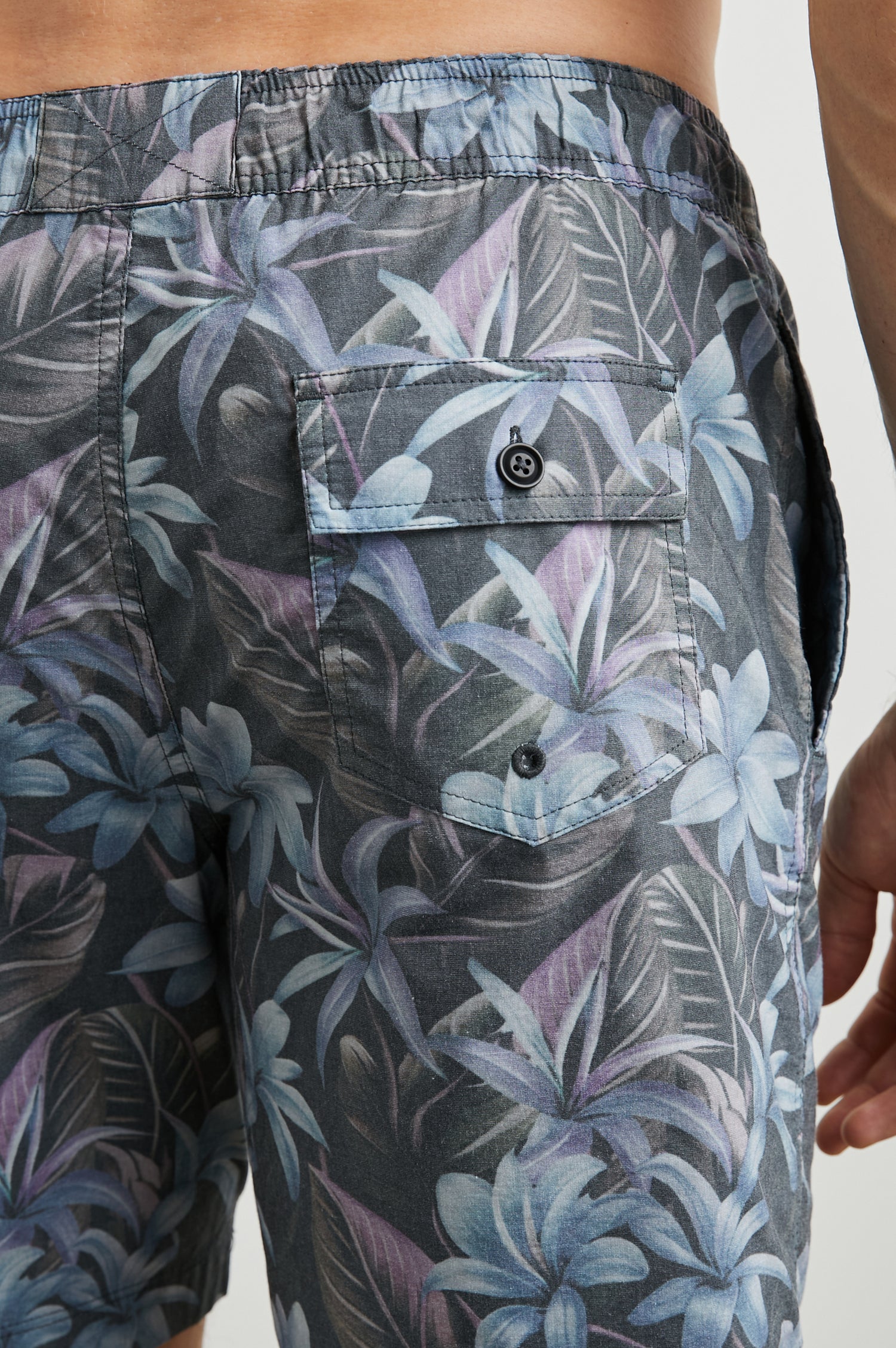 Kian Swim Shorts with an Elastic Drawstring Waistband, Two Front Pockets and a Back Button Flap Pocket in Jungle Garden Midnight Colorway, Plants on muted Pinks, blues and Greens on Black - Back View Featured on Model
