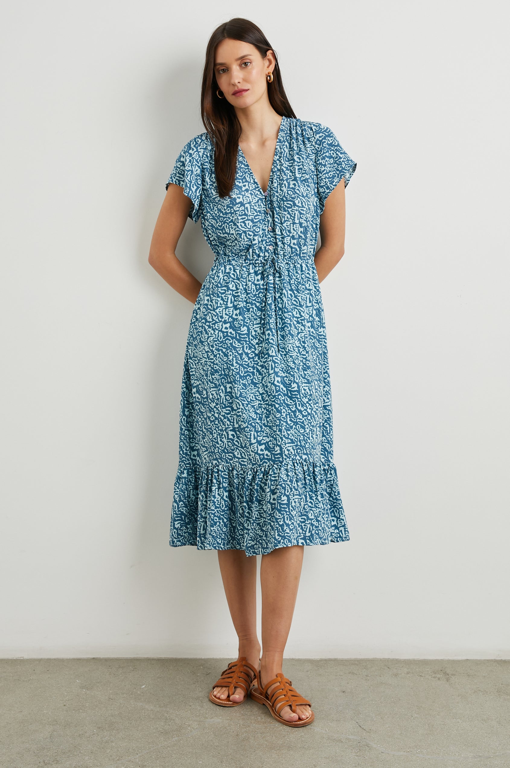 Kiki Short Sleeve Midi Dress with a V Neck, Buttons Down the Front Bodice, a Drawstring Waist and Ruffles at the Hem in Blue Havana Colorway, a Print in Blues - Front Full Body View Featured on Model 