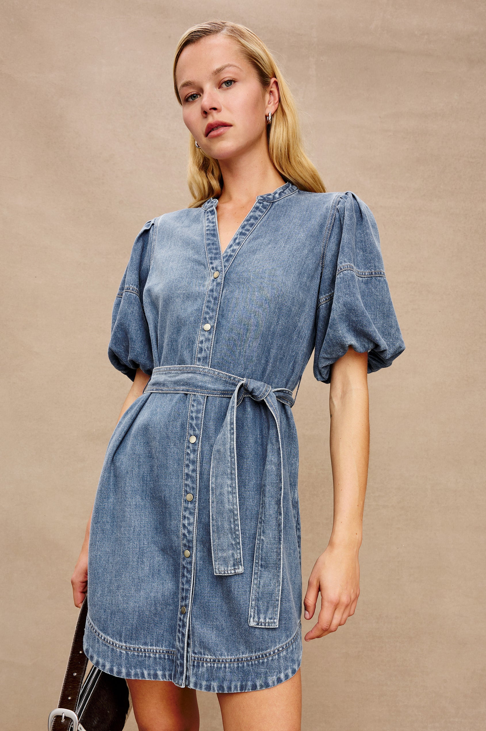 Kingsley Denim Mini Dress with Elbow-Length Puff Sleeves, a V Neck, Snaps Down the Front and a Fabric Tie Belt in Antique Blue Colorway - Stylized front view on model