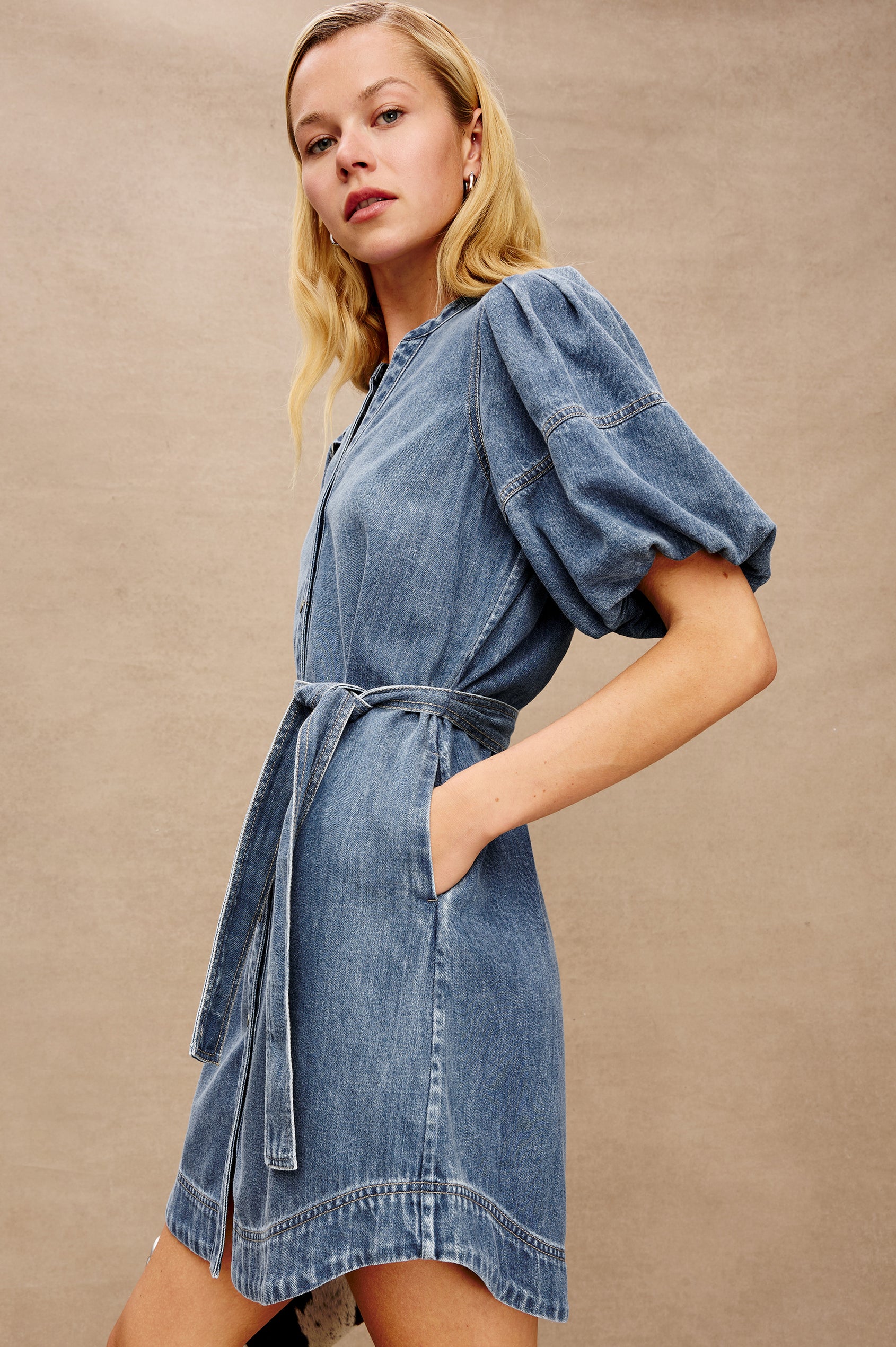 Kingsley Denim Mini Dress with Elbow-Length Puff Sleeves, a V Neck, Snaps Down the Front and a Fabric Tie Belt in Antique Blue Colorway - side view on model