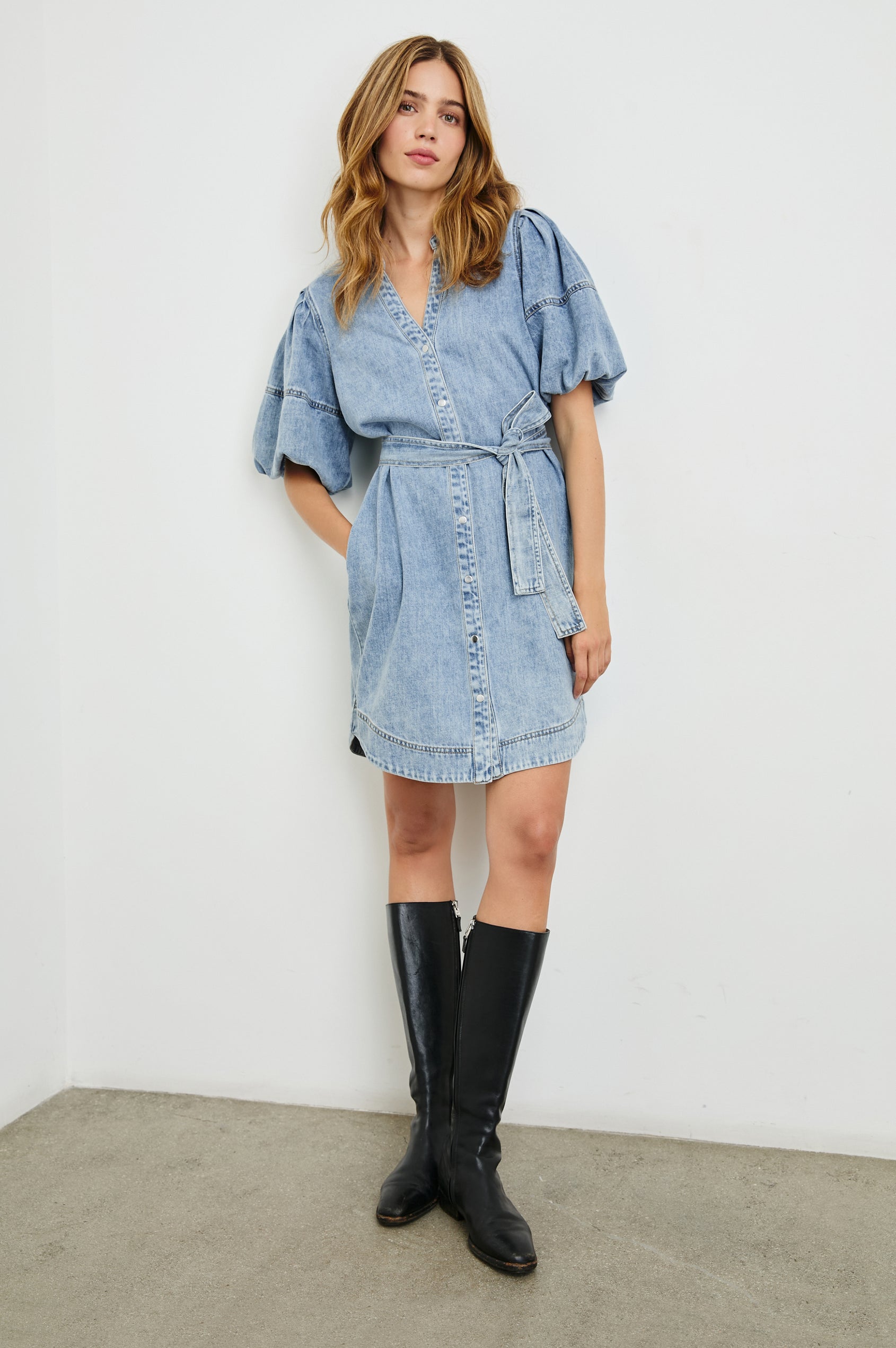 Kingsley Denim Mini Dress with Elbow-Length Puff Sleeves, a V Neck, Snaps Down the Front and a Fabric Tie Belt in Faded Indigo Colorway - Front Full Body View Featured on Model 