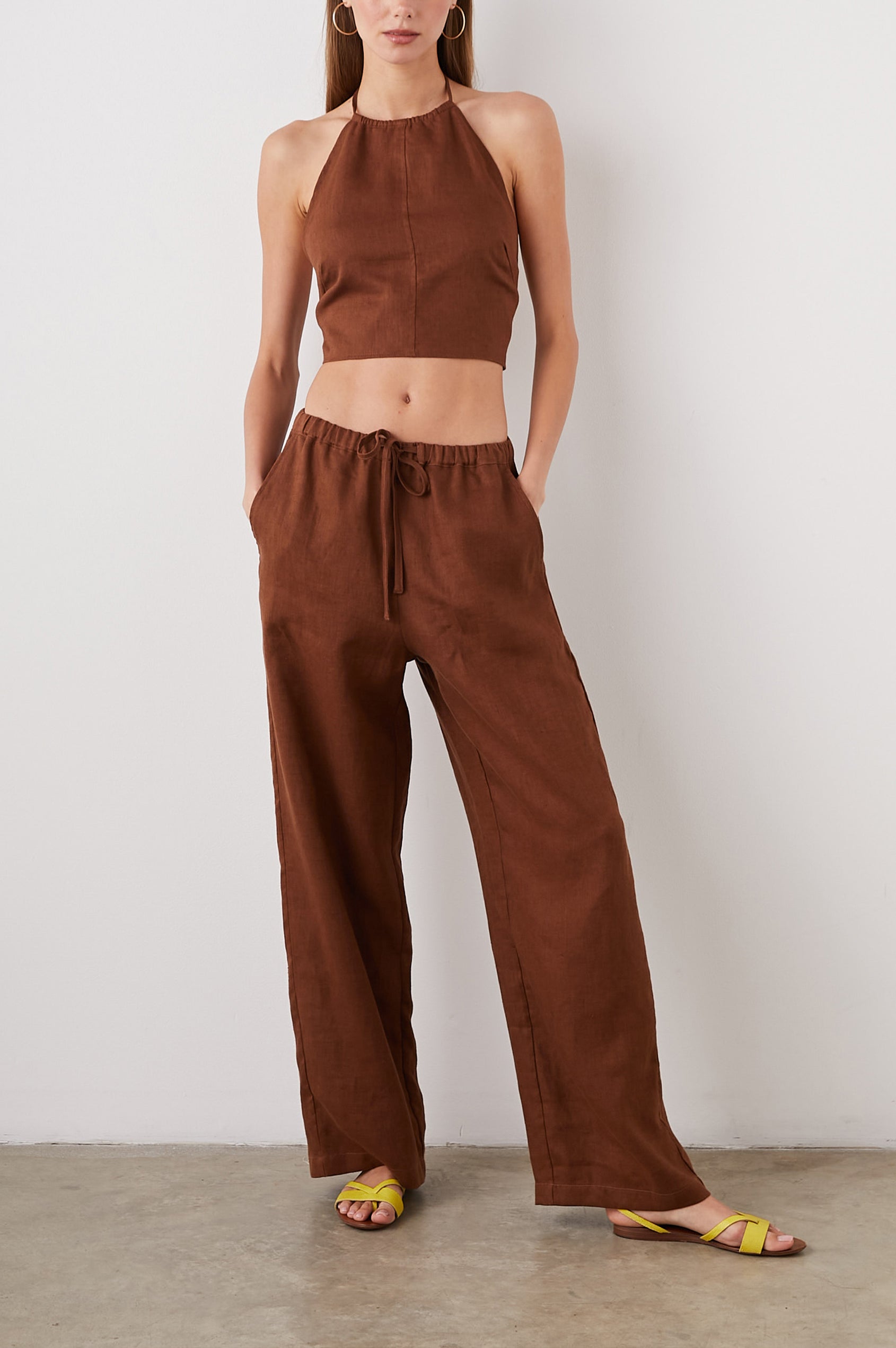 Kyra Sleeveless Crop Top with a Halter Neckline with a Back Neck Tie, an Open Back with Two Tie Closure and a Vertical Seam at the Front Center in Cacao Colorway - Front Full Body View Featured on Model  