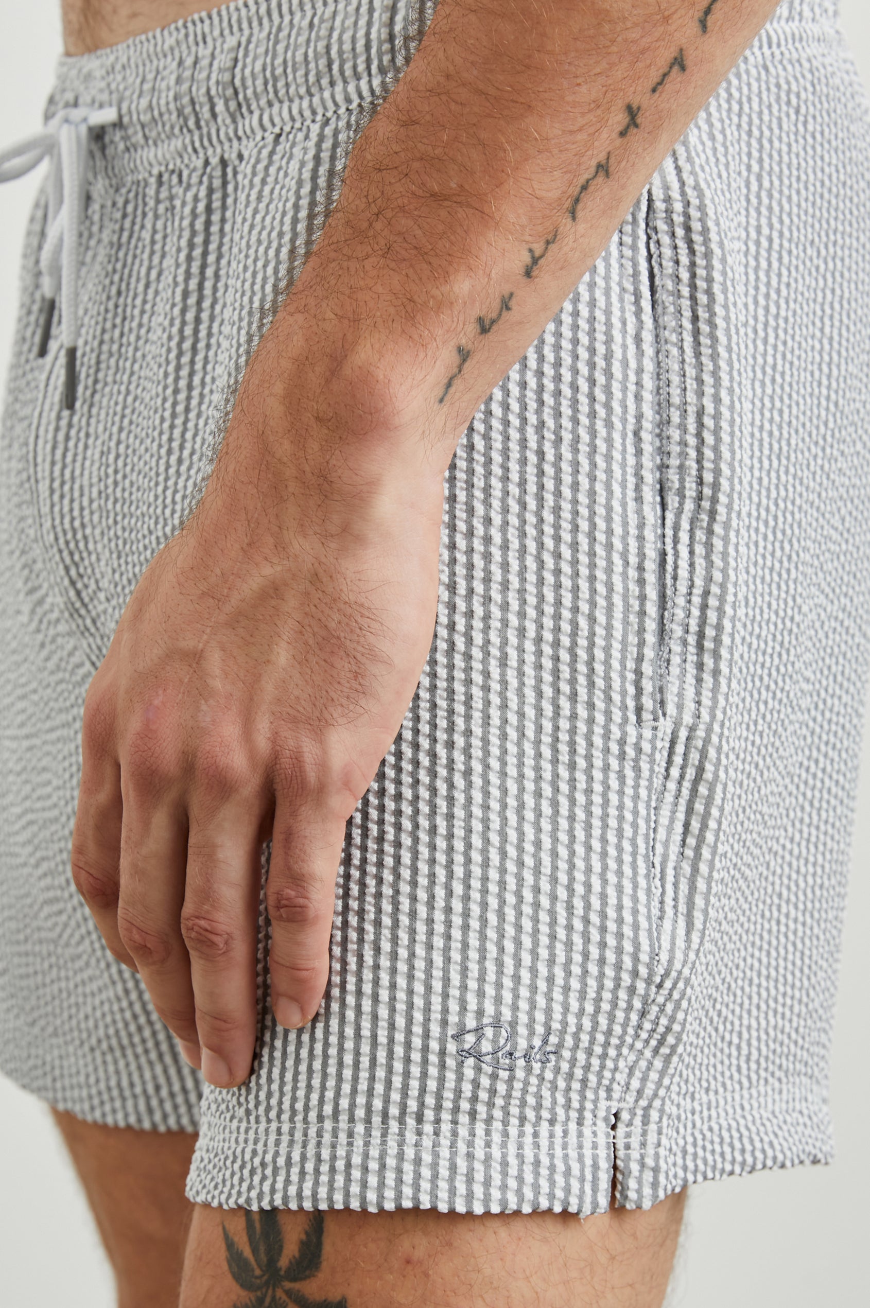 La Brea Swim Shorts with a Drawstring Waist, Two Front Pockets and a Back Patch Pocket in Faded Seersucker Colorway, Grey and white thin vertical stripes - Side View Featured on Model