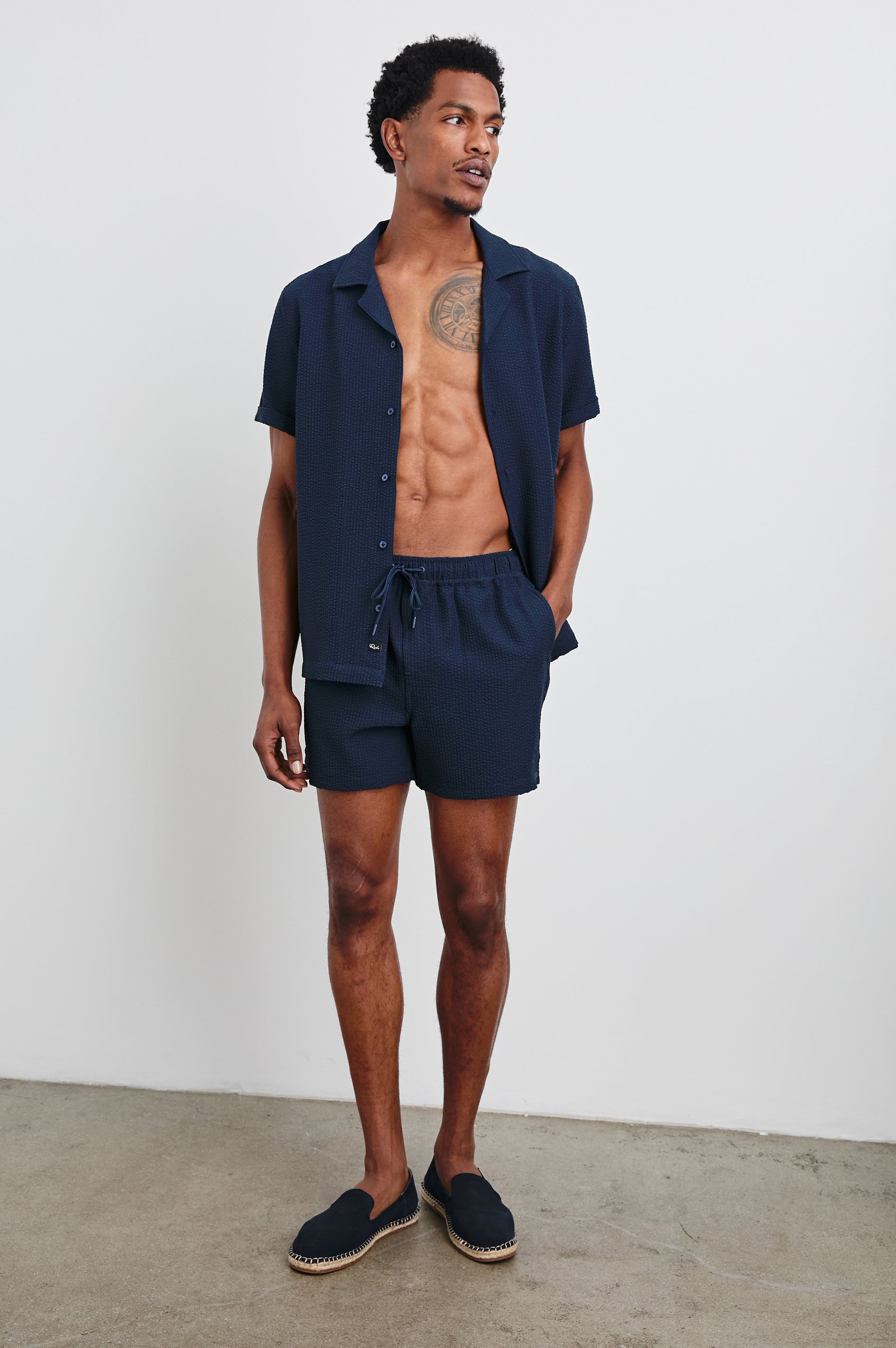 La Brea textured mid-length swim short with adjustable waist drawstring in Navy Seersucker - full body front view on model, shirt unbuttoned