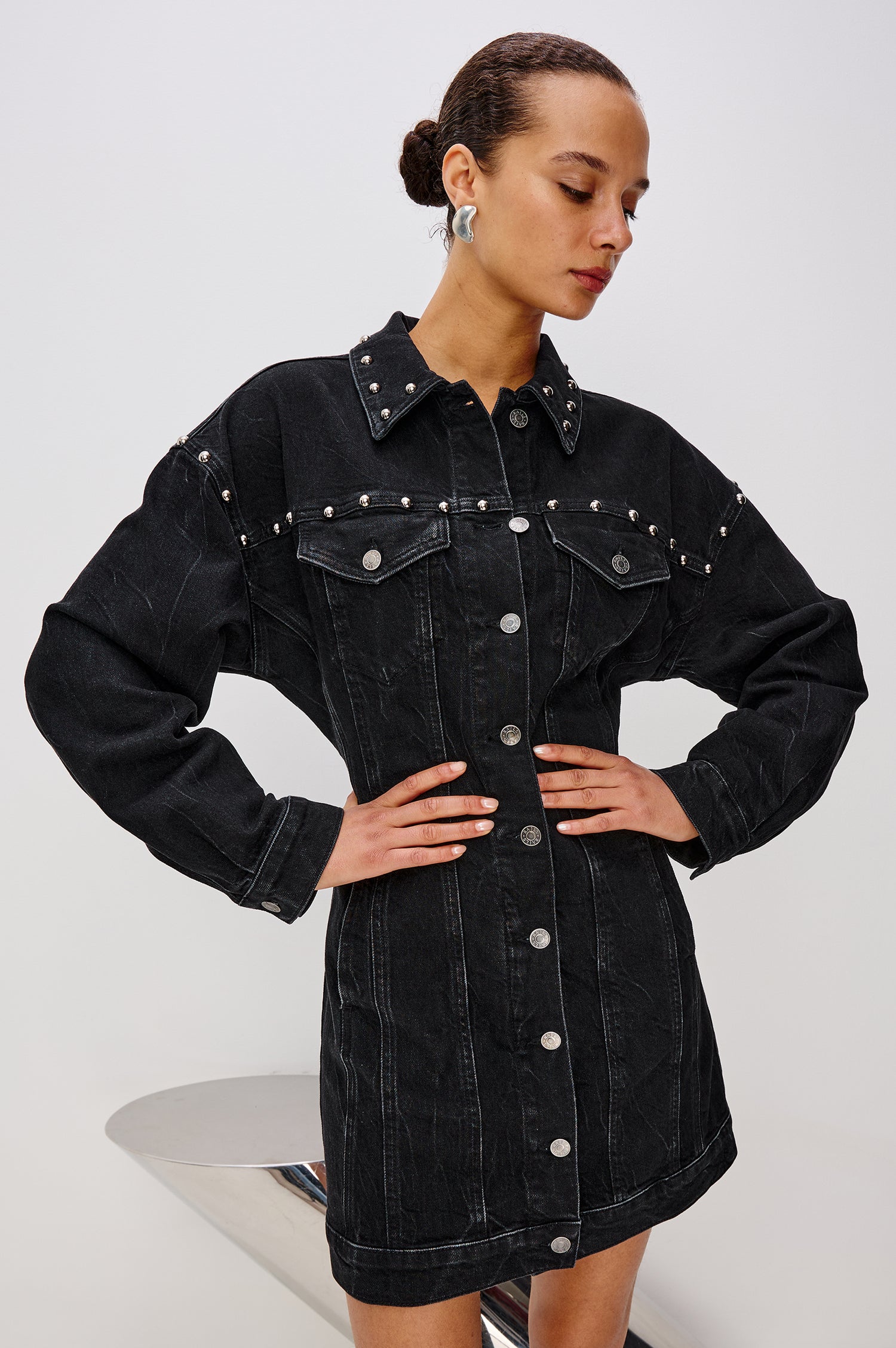 Ladera Mini Dress in Denim With Subtle Stretch, Drop Shoulders, Collar, Relaxed Long Balloon Sleeves, Nail-Back Studs, Front Buttons, A-Line Shape, and Adjustable Back Strap in Black Stone Studded Colorway - Upper Body Close Up Front View Featured on Model