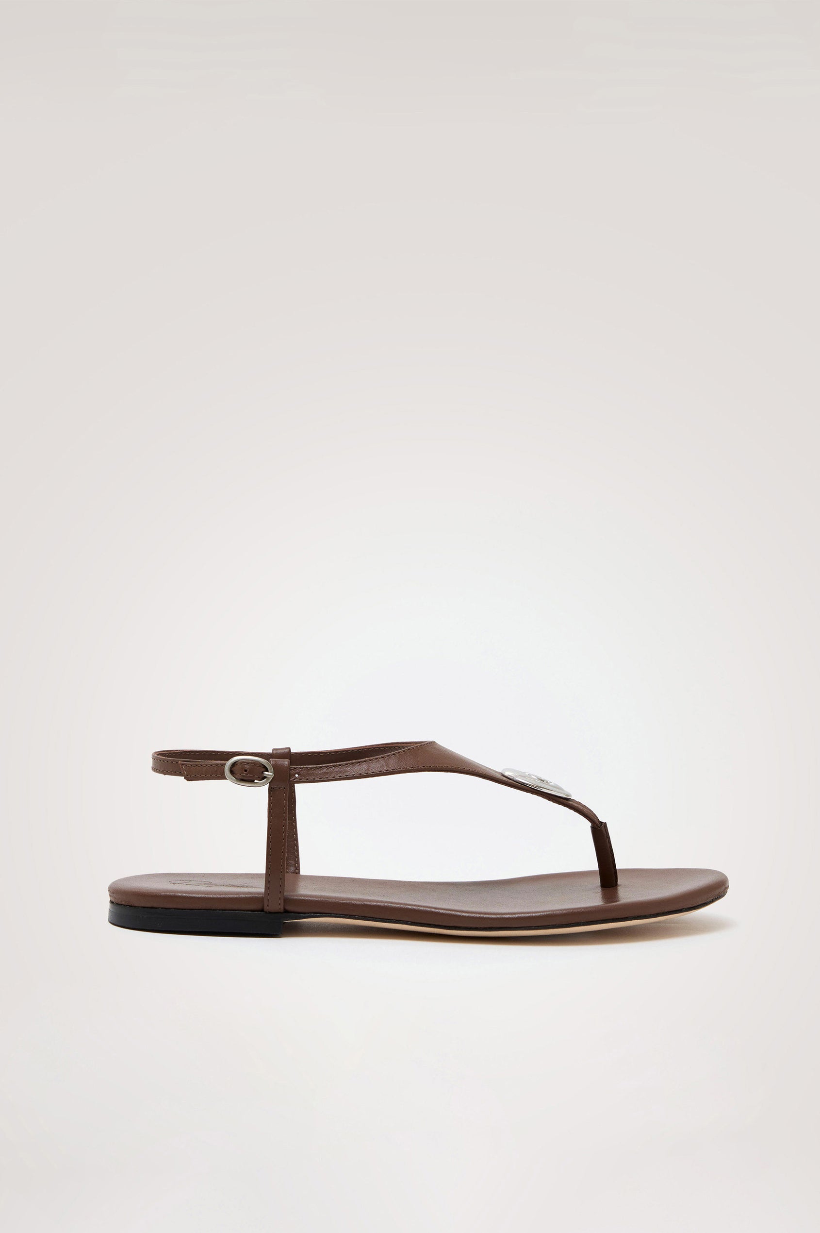 Lagos T-Strap Sandal in Leather With Adjustable Buckled Ankle Straps and Molded Silver Hardware Detail in Dark Brown Colorway - Side View Featured