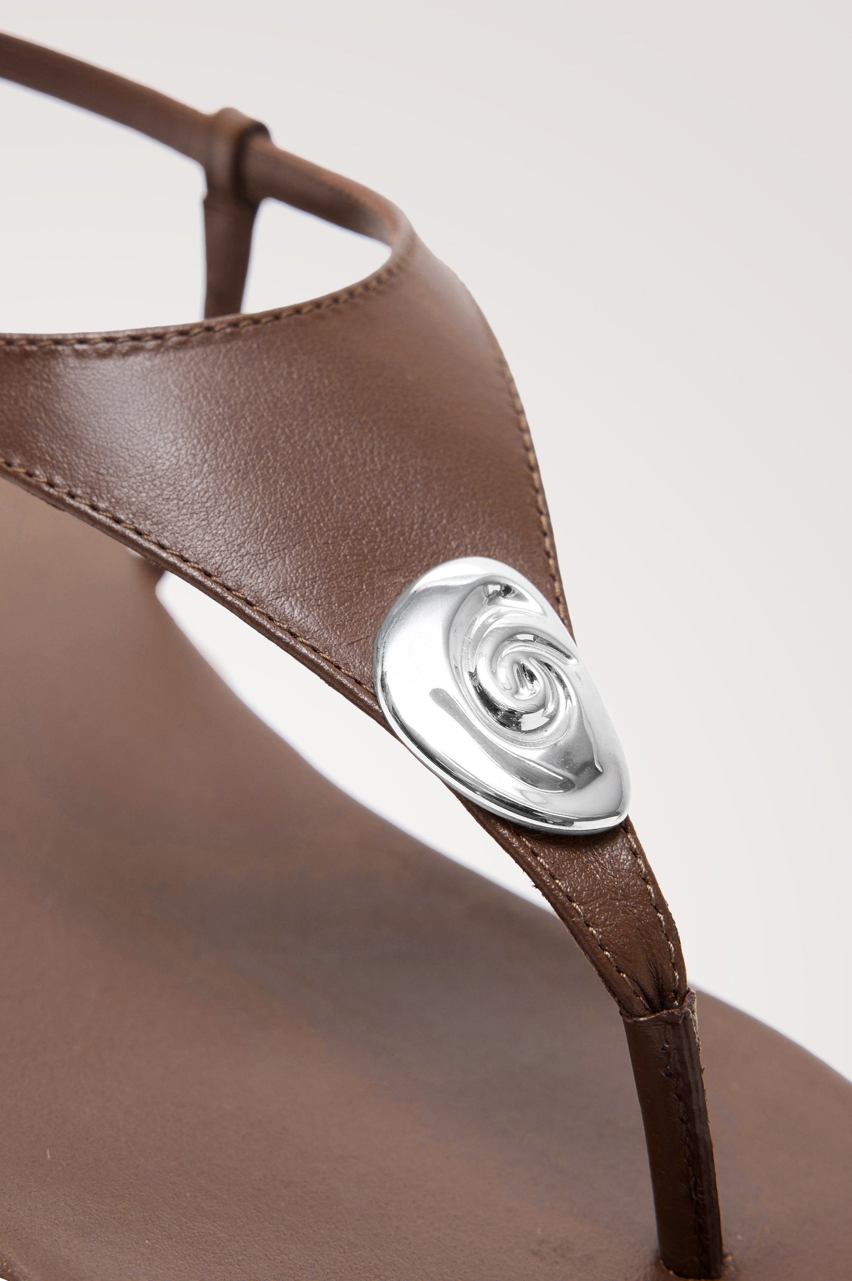 Lagos T-Strap Sandal in Leather With Adjustable Buckled Ankle Straps and Molded Silver Hardware Detail in Dark Brown Colorway - Side View Featured