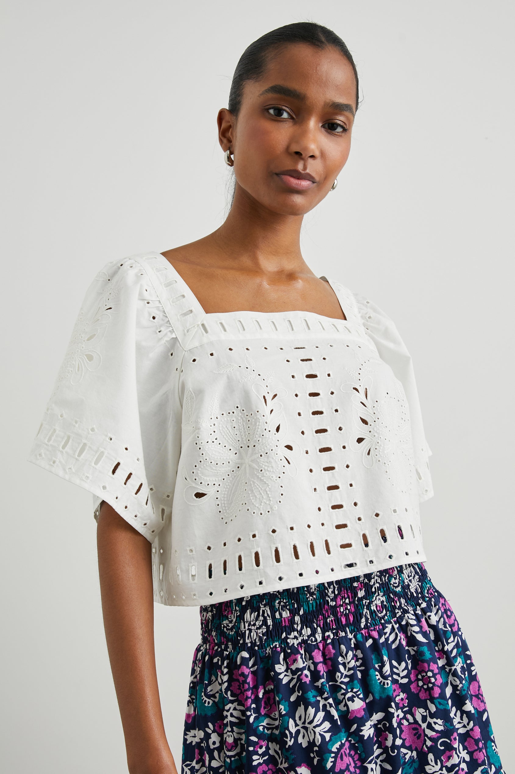 Laine Short Sleeve Crop Top with Square Neckline, and a Floral and Geometric Eyelet Design in White Colorway - Front View Featured on Model