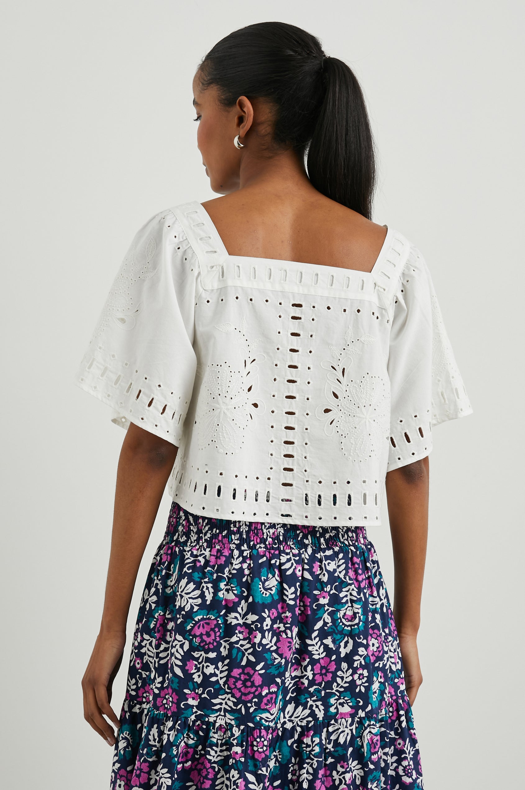 Laine Short Sleeve Crop Top with Square Neckline, and a Floral and Geometric Eyelet Design in White Colorway - Back View Featured on Model