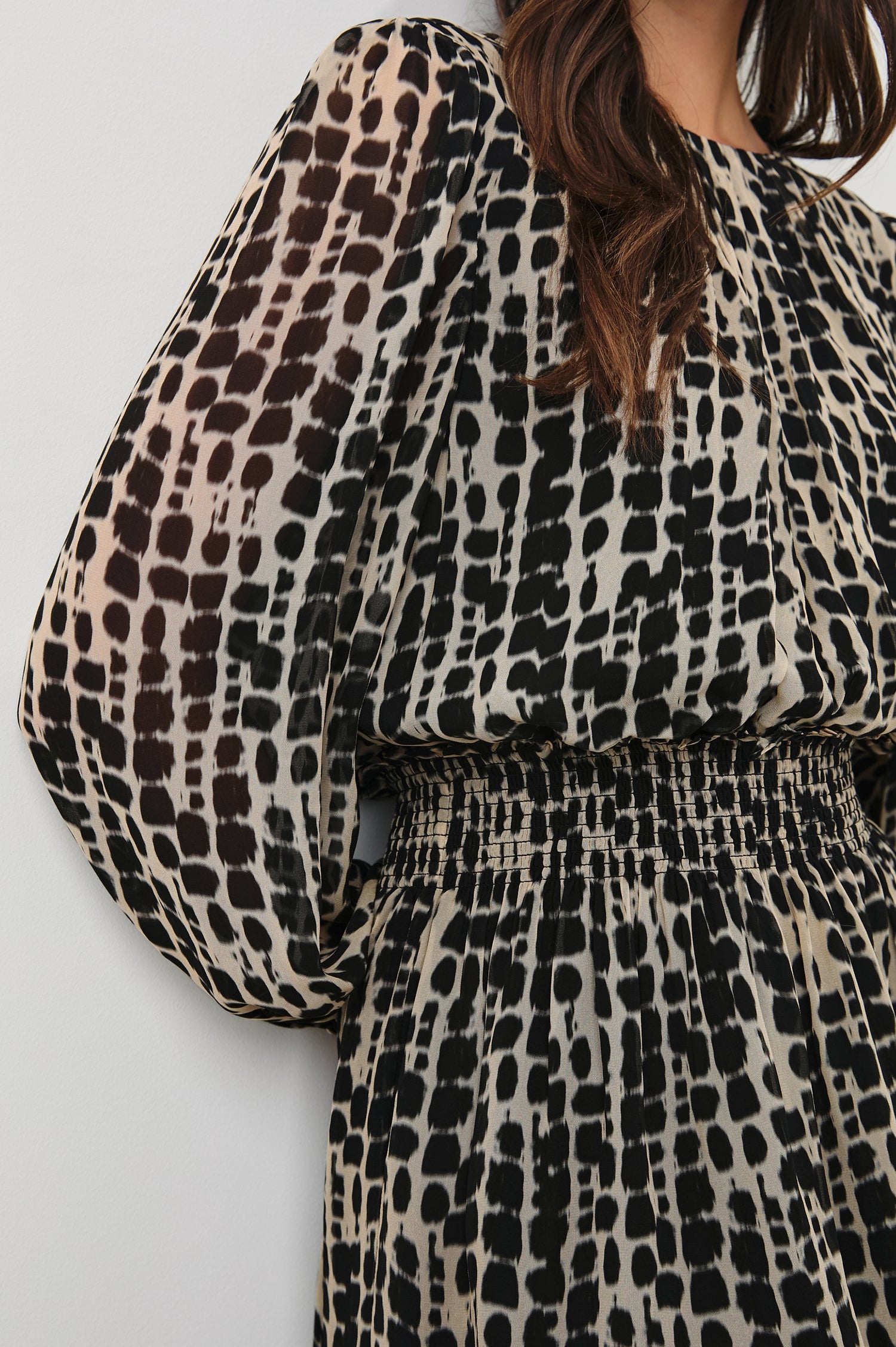 Lanie Long-Sleeve Mini Dress with a Crew Neck, Smocked Waist, and Elastic Cuffs in Spotted Shibori Colorway, a Tan and Black Pattern - Front View Featured on Model