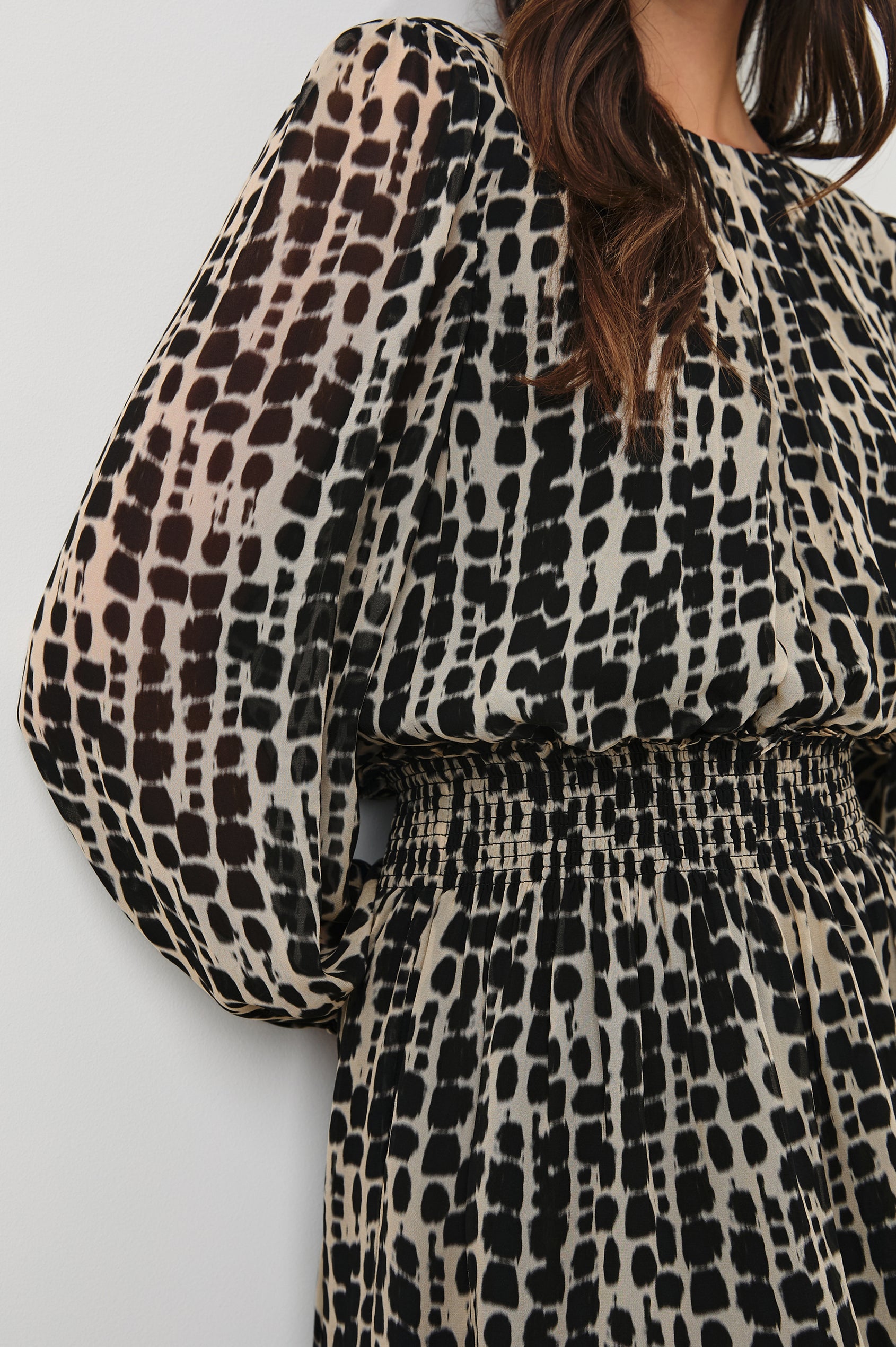 Lanie Long-Sleeve Mini Dress with a Crew Neck, Smocked Waist, and Elastic Cuffs in Spotted Shibori Colorway, a Tan and Black Pattern - Front View Featured on Model