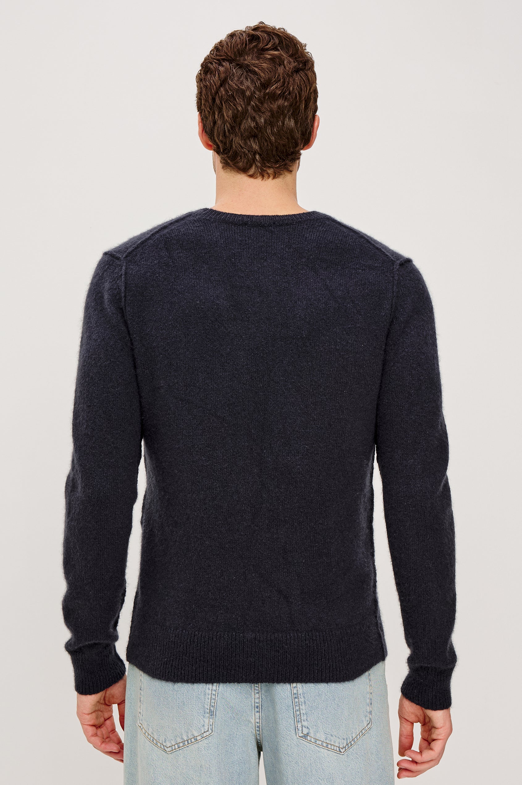 The Laurent is a relaxed-fit sweater with dropped shoulders, long sleeves, and linking-stitch detailing at the shoulders in Midnight colorway. Back view featured on model.