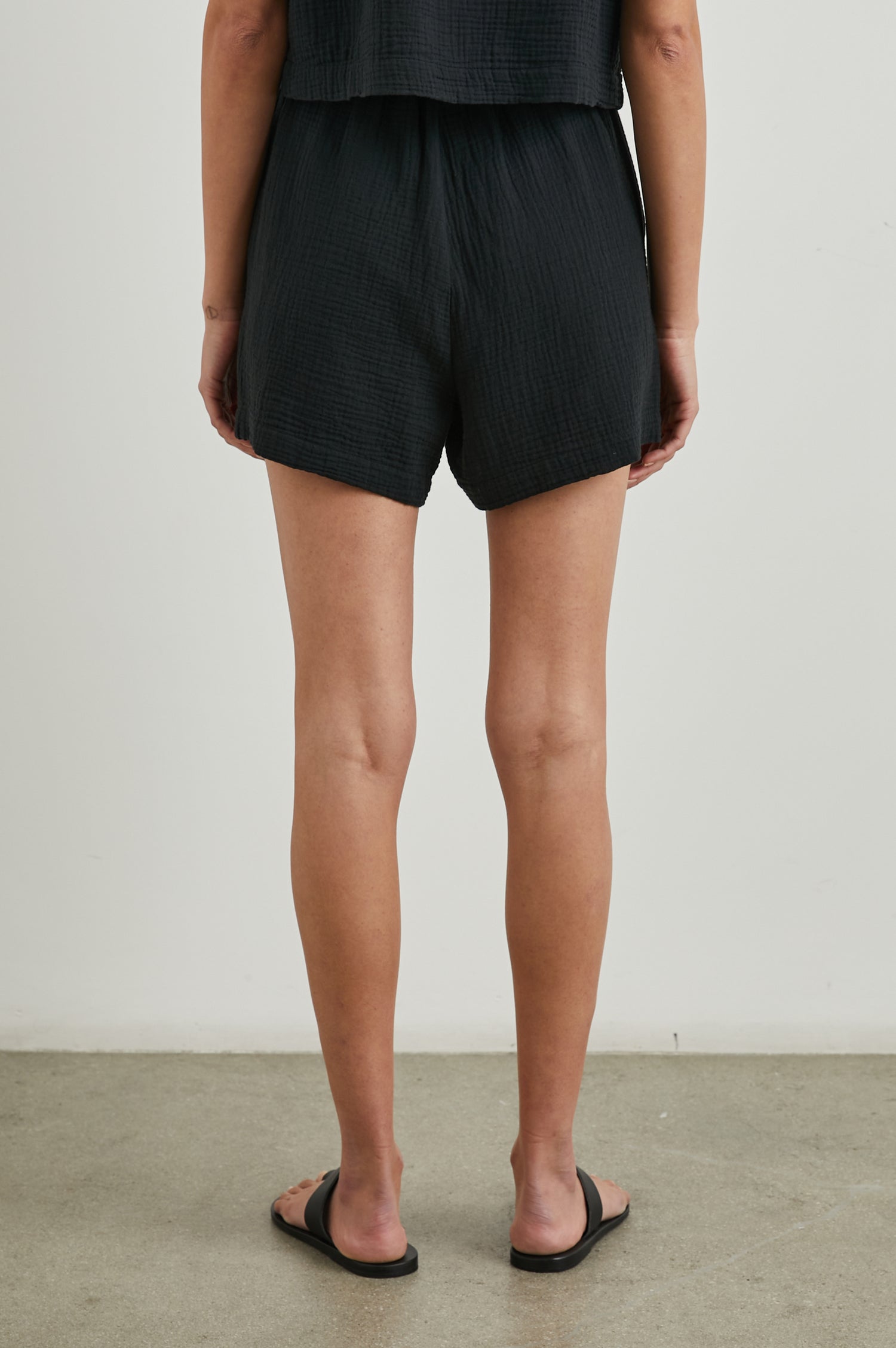 Leighton Shorts with Textured Fabric, a Smocked Elastic Waist, and Large Front Pockets in Black Colorway - Back View Featured on Model