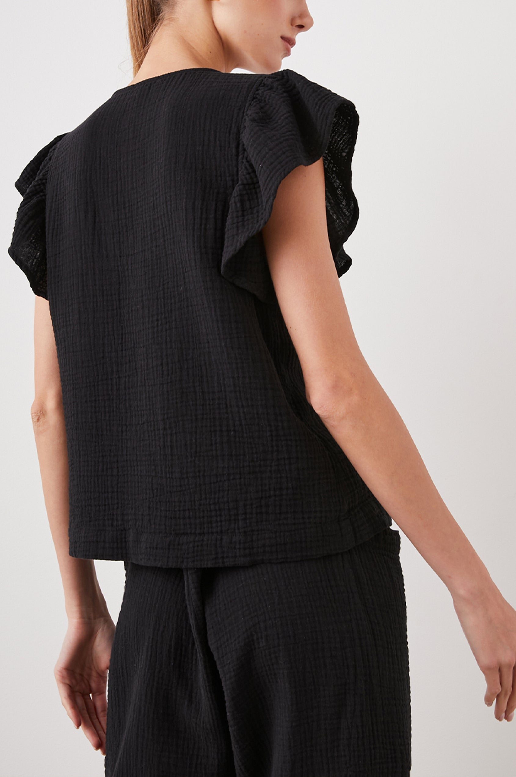 Lela Short-Sleeve Top with Flutter Sleeves and a V Neck in Black Colorway - Back View Featured on Model  