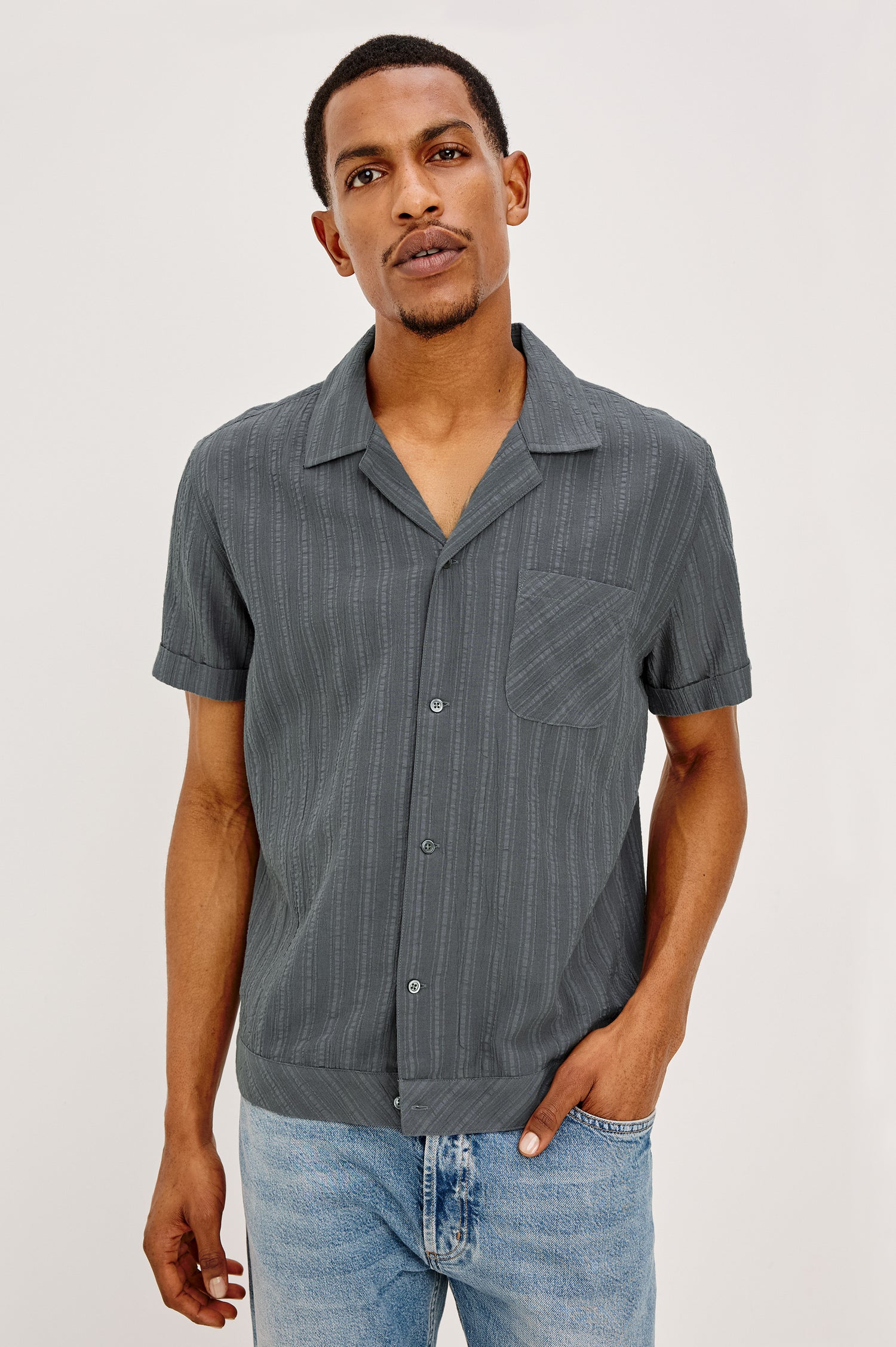 Lemmy is a textured dobby cotton shirt. Featuring a notched collar, chest pocket, front buttons, and rolled short sleeves - front upper body view on model.
