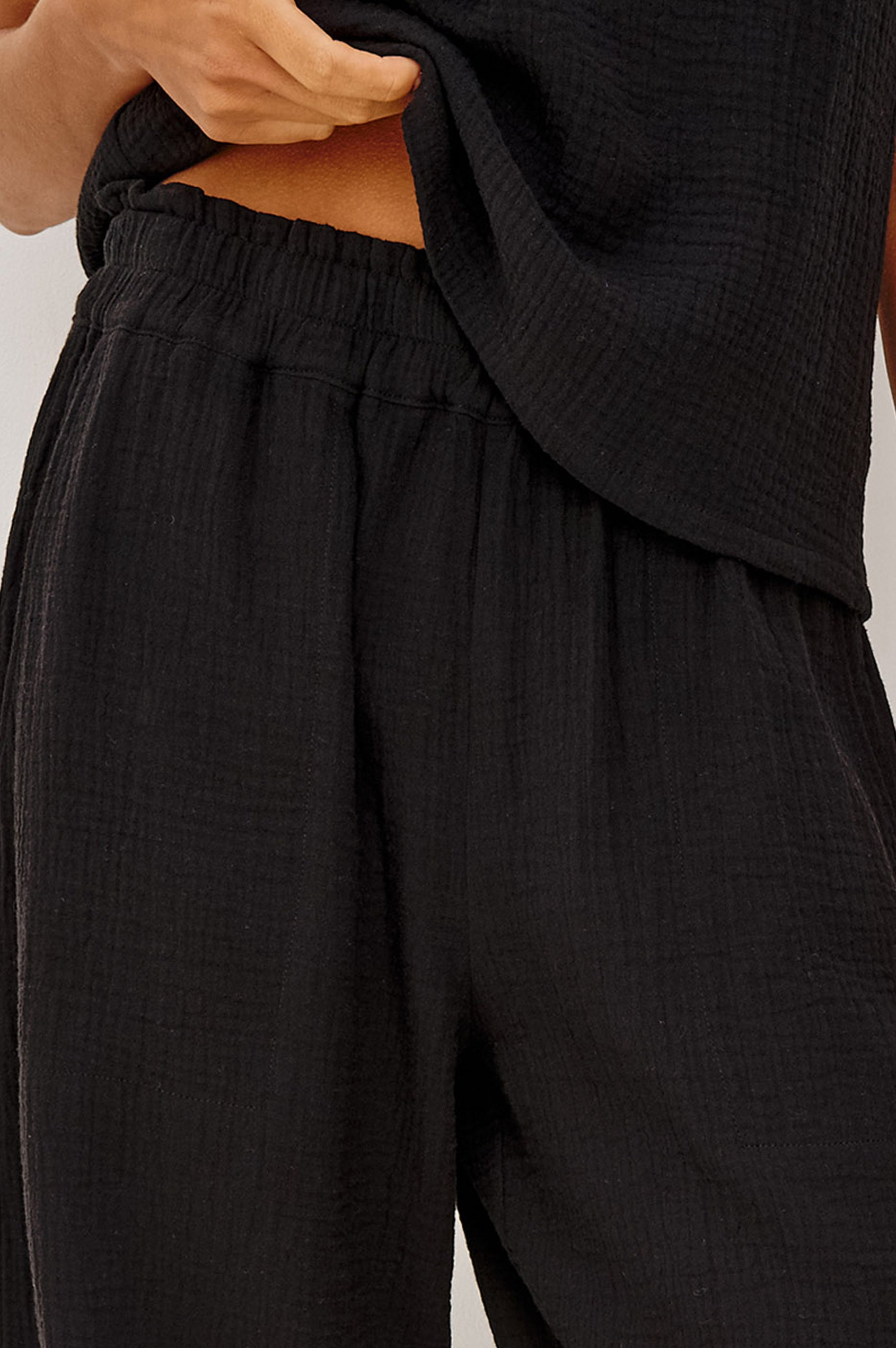 Leon Crop Cotton Gauze Pant With Hemline Slit And Elastic Waist In Colorway Black - Front Detail View Featured On Model