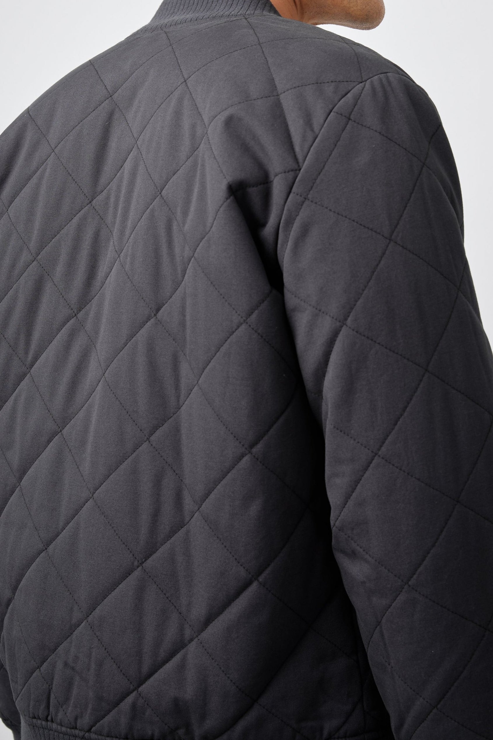 Peninsula Jacket with Zip Closure, Two Front Pockets, an Inner Zippered Pocket, a Quilted Pattern and Ribbed Trim in Washed Black Colorway - Back View Featured on Model