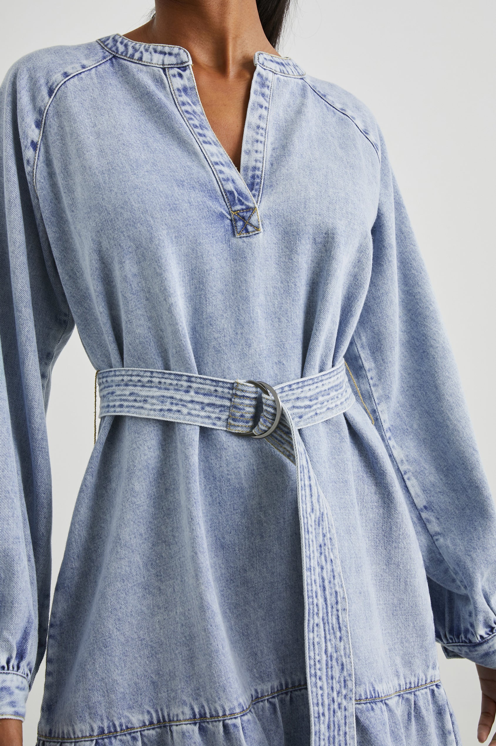 Lila Long-Sleeve Denim Mini Dress with a Fabric Double Ring Belt, a V Neck and Snap Cuffs in Faded Indigo Colorway - Front View Featured on Model 