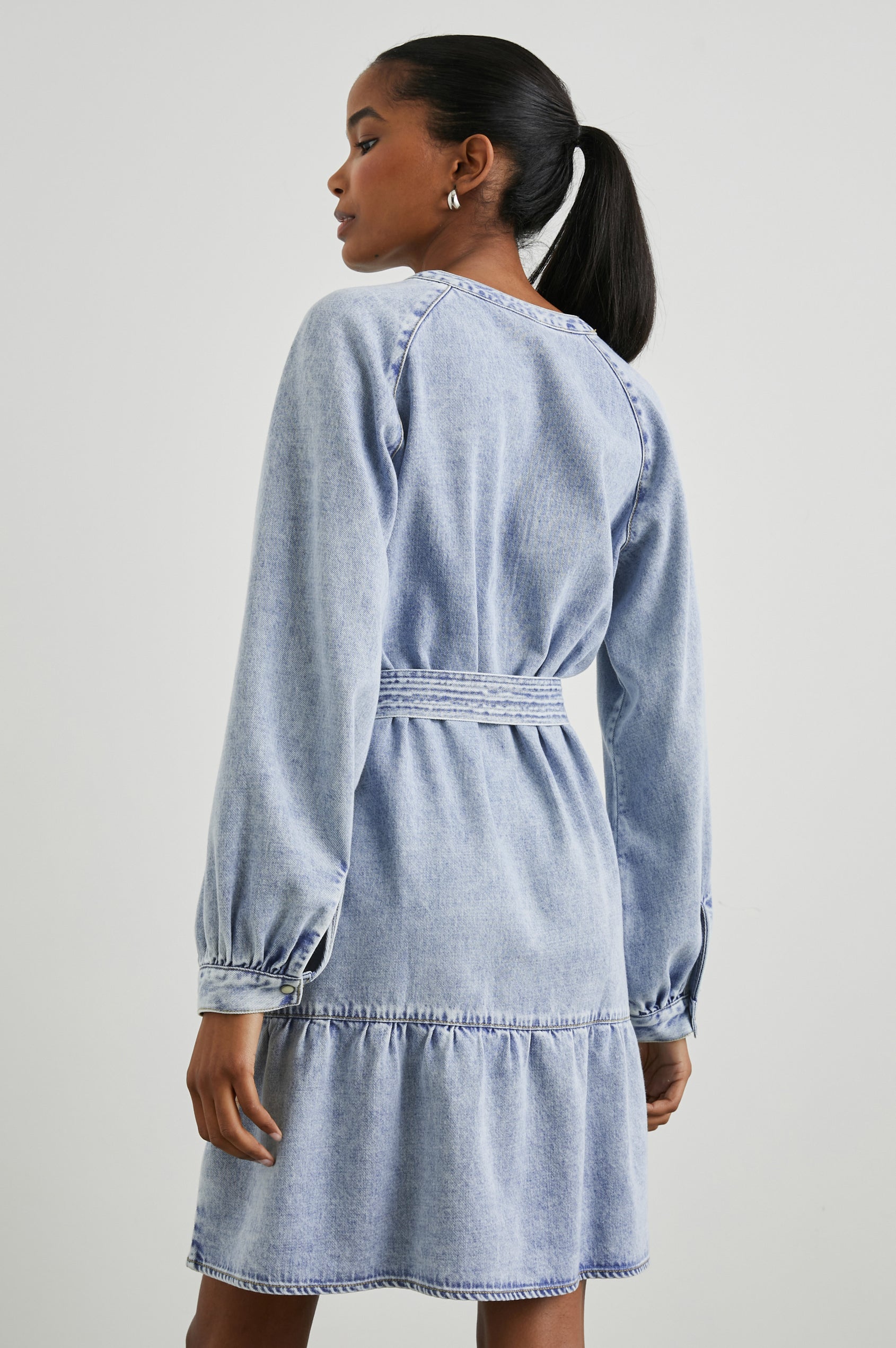 Lila Long-Sleeve Denim Mini Dress with a Fabric Double Ring Belt, a V Neck and Snap Cuffs in Faded Indigo Colorway - Back View Featured on Model 