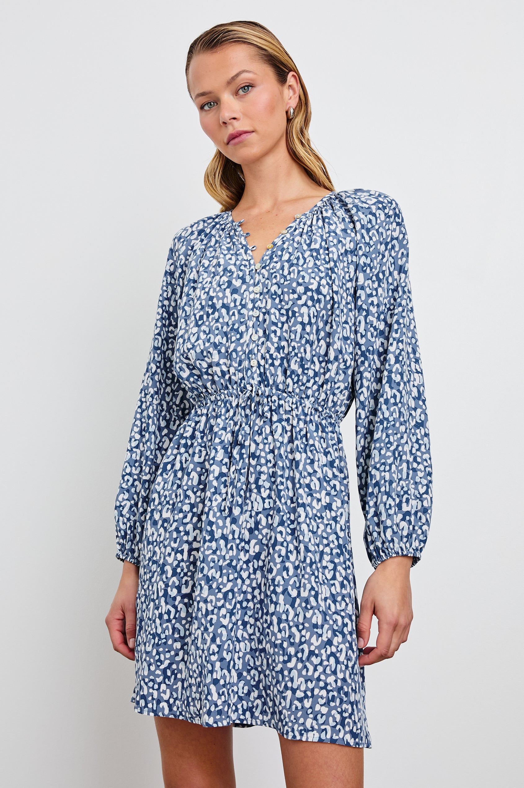 Linnea Mid-Thigh, Long-Sleeve Dress with a V Neck, Buttons down the Bodice, a Smocked Waist with Drawstring, and Elastic Cuffs in Blue Mixed Cheetah Colorway, Spots in Blues and White - Front View Featured on Model