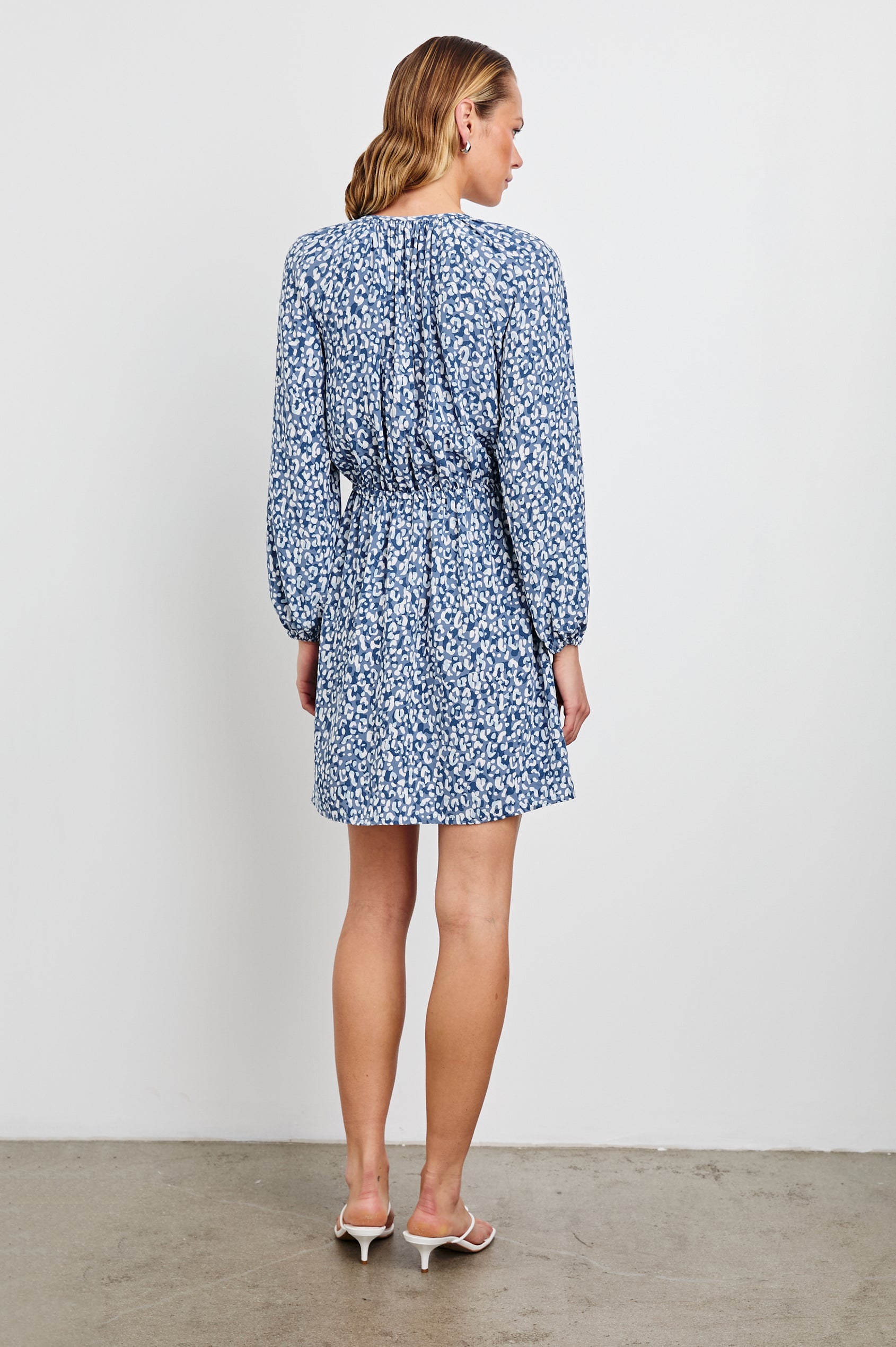Linnea Mid-Thigh, Long-Sleeve Dress with a V Neck, Buttons down the Bodice, a Smocked Waist with Drawstring, and Elastic Cuffs in Blue Mixed Cheetah Colorway, Spots in Blues and White - Back View Featured on Model