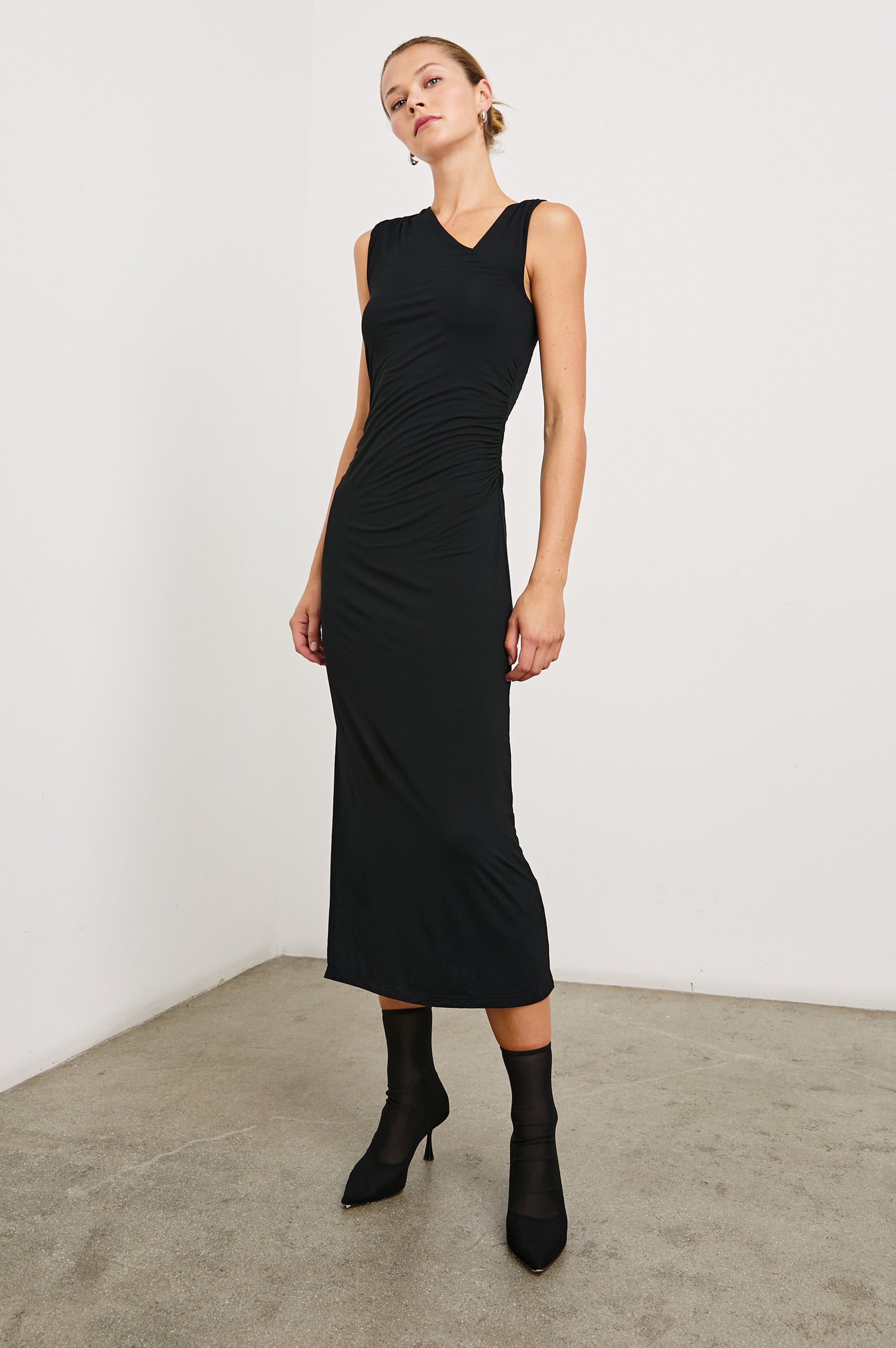 Lola Sleeveless Midi Dress with Ruching Along Both Bodice Sides, a Mid-Thigh Side Slit and an Asymmetrical Neckline in Black Onyx Colorway - Front Full Body View Featured on Model