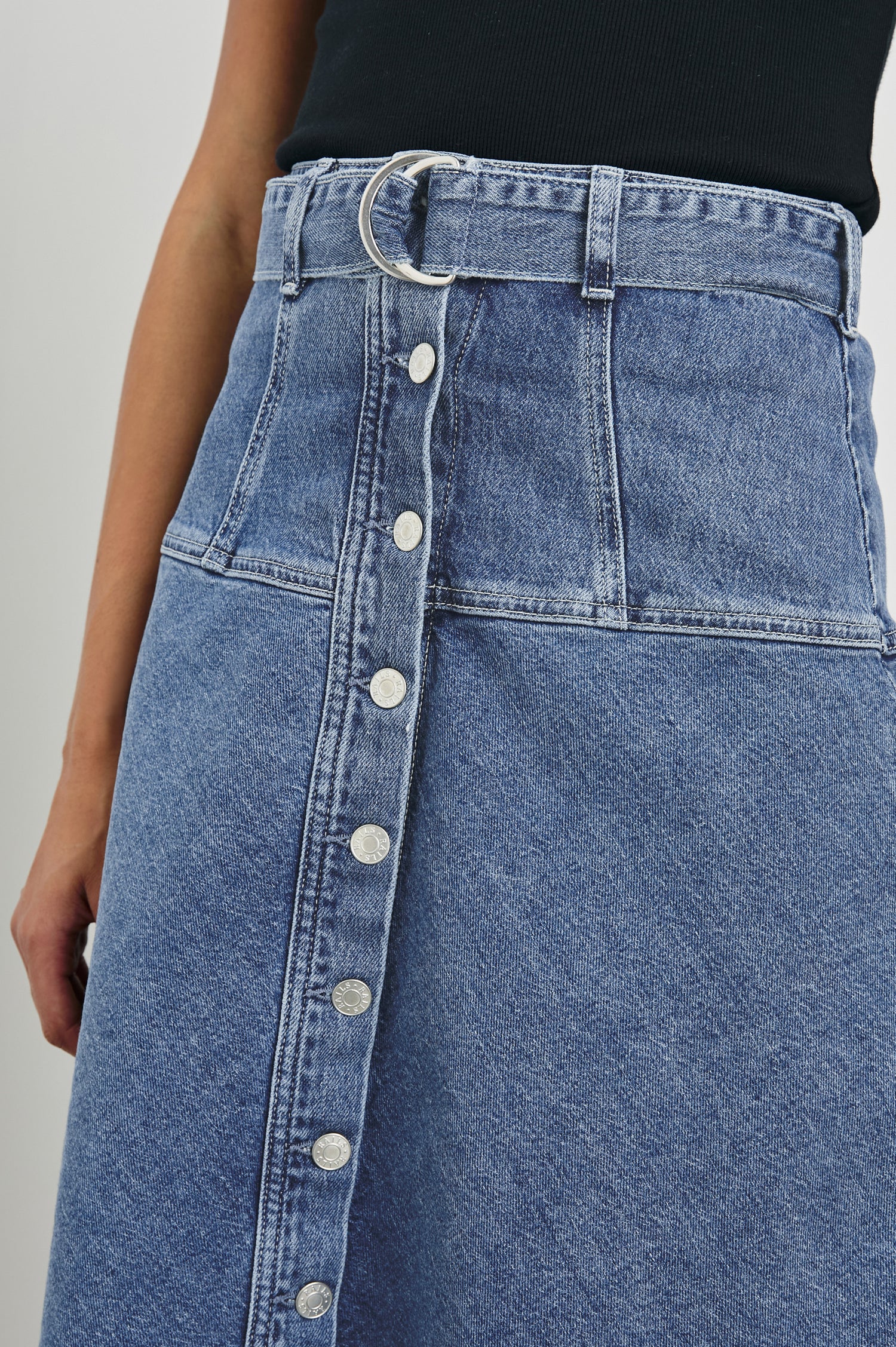 Loma Below-Knee A-Line Denim Skirt with an Exposed Button Front Opening, Adjustable Self Belt with D-Ring Closure and Stitching Details on Waist/Hip in Pacific Coast Colorway. Front Detailed View Shown on Model.