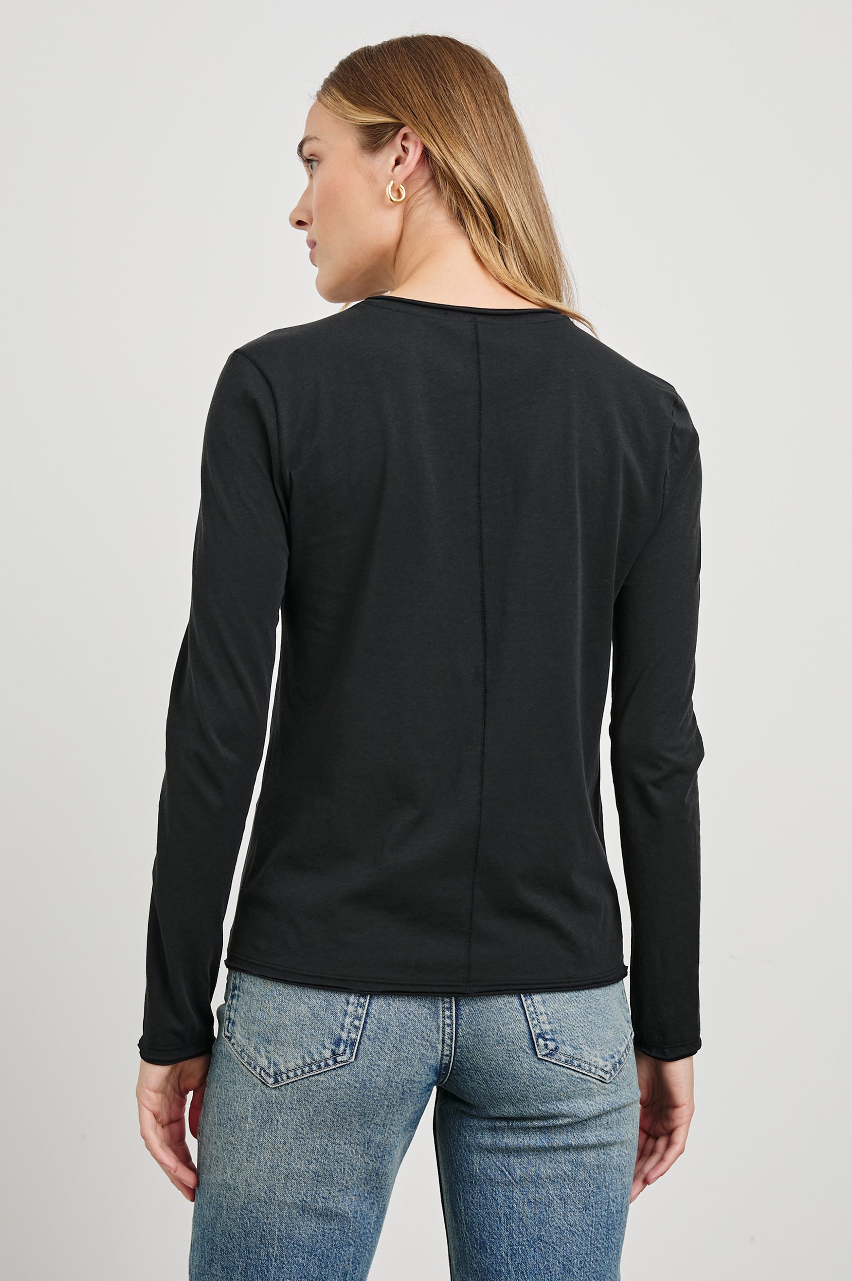 Long Sleeve Crew Neck T Shirt with Raw Hem, Collar and Cuffs in Black Colorway - Back View Featured on Model