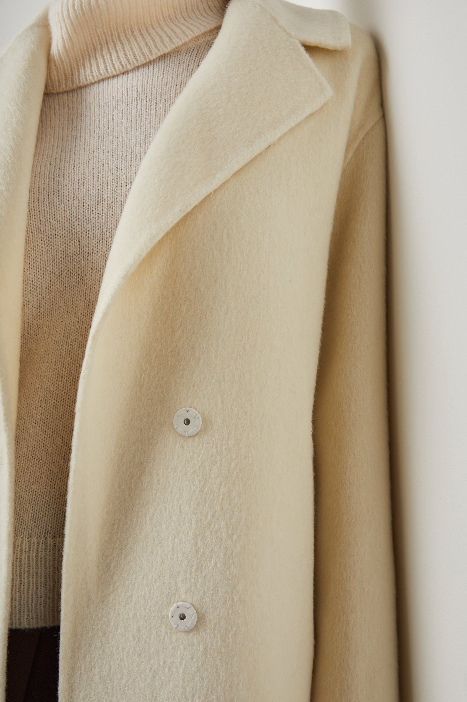 Lore Knee-Length Coat with Two Button Closure, Notched Lapels and Two Front Pockets in Ivory Colorway - Front View Featured on Model