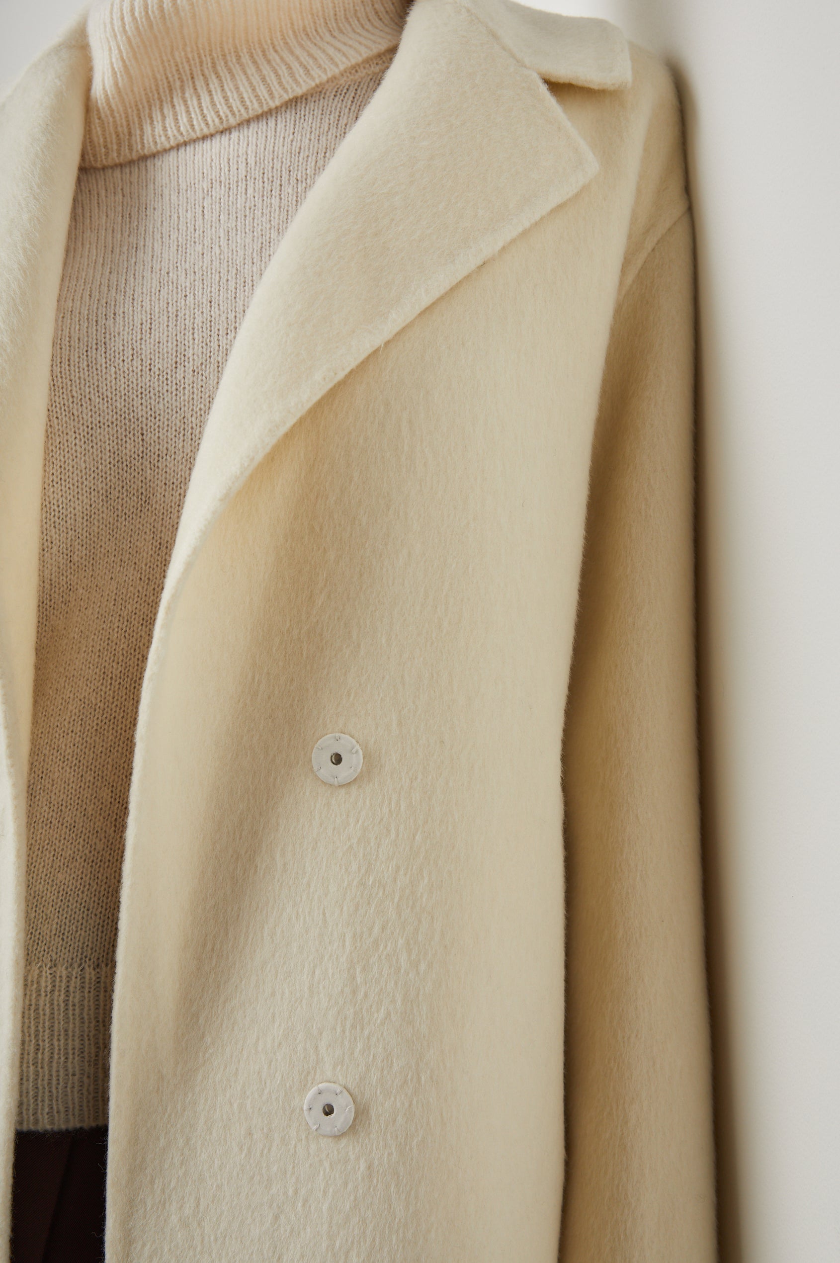 Lore Knee-Length Coat with Two Button Closure, Notched Lapels and Two Front Pockets in Ivory Colorway - Front View Featured on Model